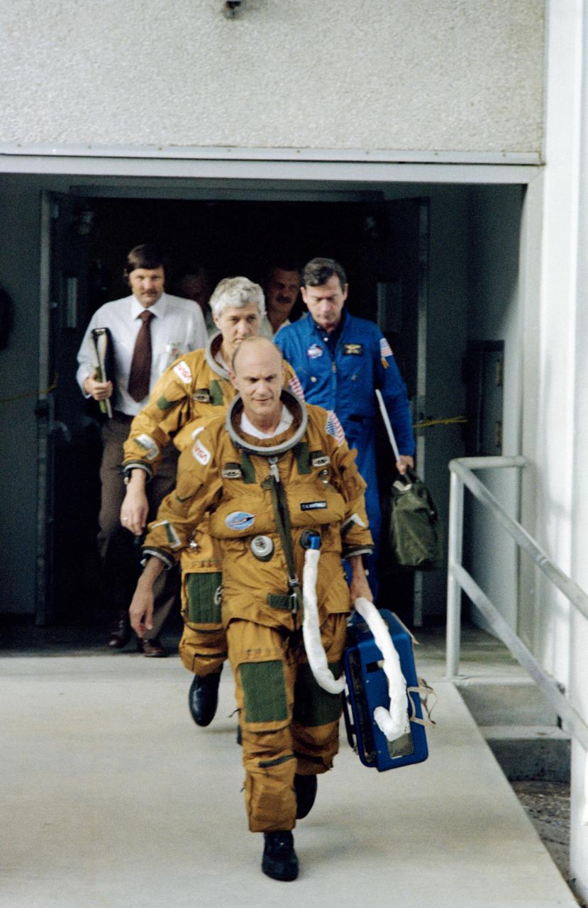 S82-32202 (29 May 1982) --- Astronauts Thomas K. (Ken) Mattingly II, center foreground, and Henry W. Hartsfield Jr., both wearing pressure garments, leave the operations and checkout building at KSC to board a special van that will take them to Launch Pad 39A for a rehearsal for their liftoff. Accompanying the pair are astronaut John W. Young (blue flight suit), chief of the astronaut office at JSC; Richard W. Nygren of the vehicle integration test team (VITT); and James O. Schlosser, space suit engineer. Photo credit: NASA