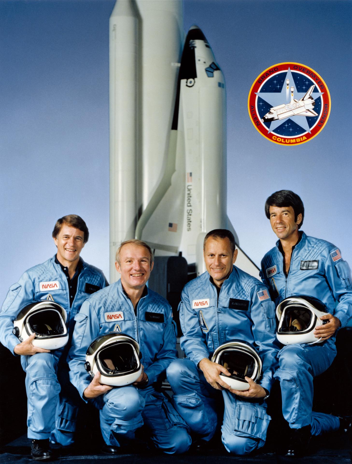 Official crew portrait for STS-5. They are astronauts Vance D. Brand (second left), STS-5 commander; Robert F. Overmyer (second right), pilot; and Joseph P. Allen (left) and William B. Lenoir, both mission specialists. They pose with a space shuttle model and the official insignia for STS-5.