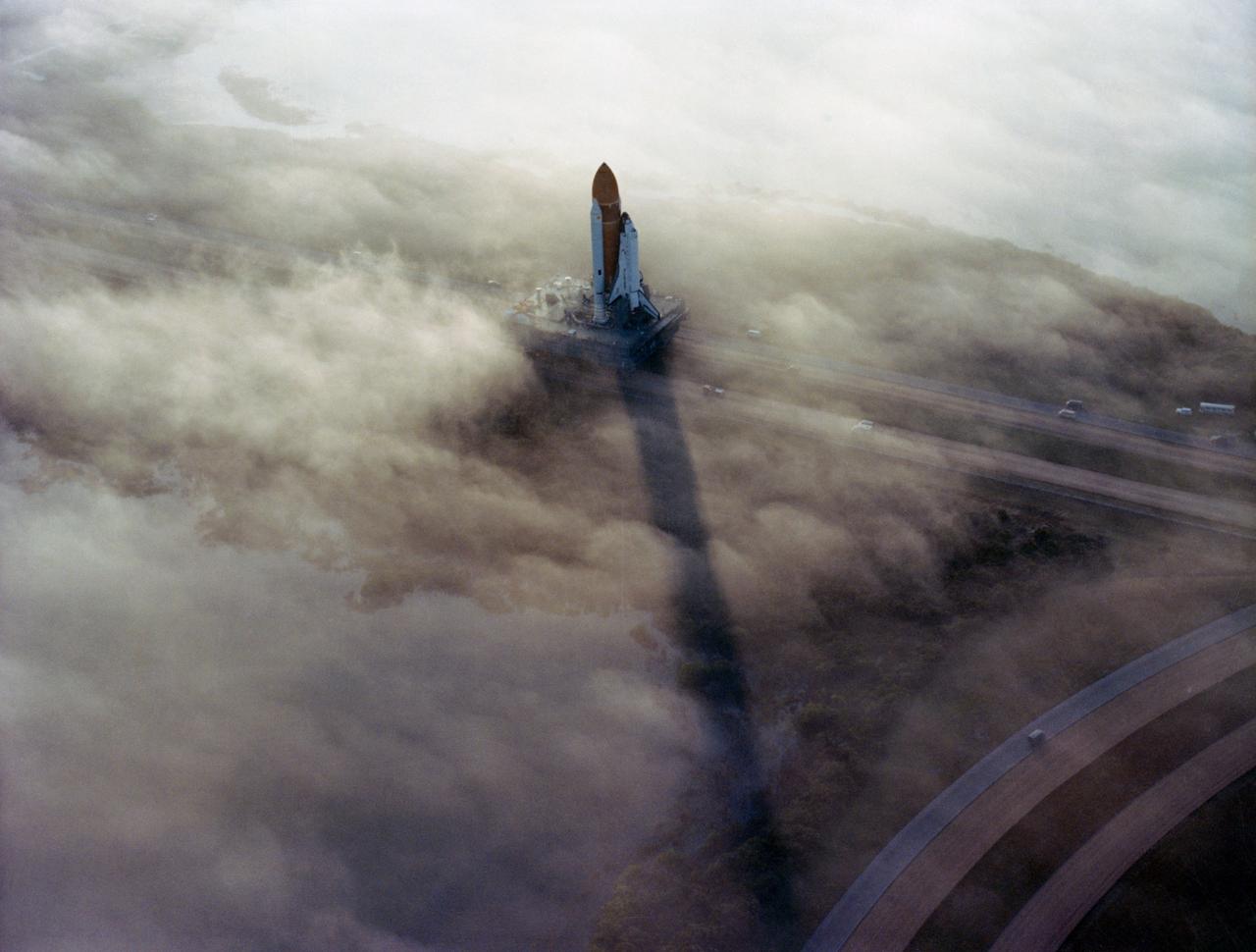 Two (2) views of the "Challenger" - STS-6 -  being    Rolled Out to Pad 39A in the morning fog, 11/30/1982.      1.  KSC - STS-6 PREFLIGHT      KSC, FL