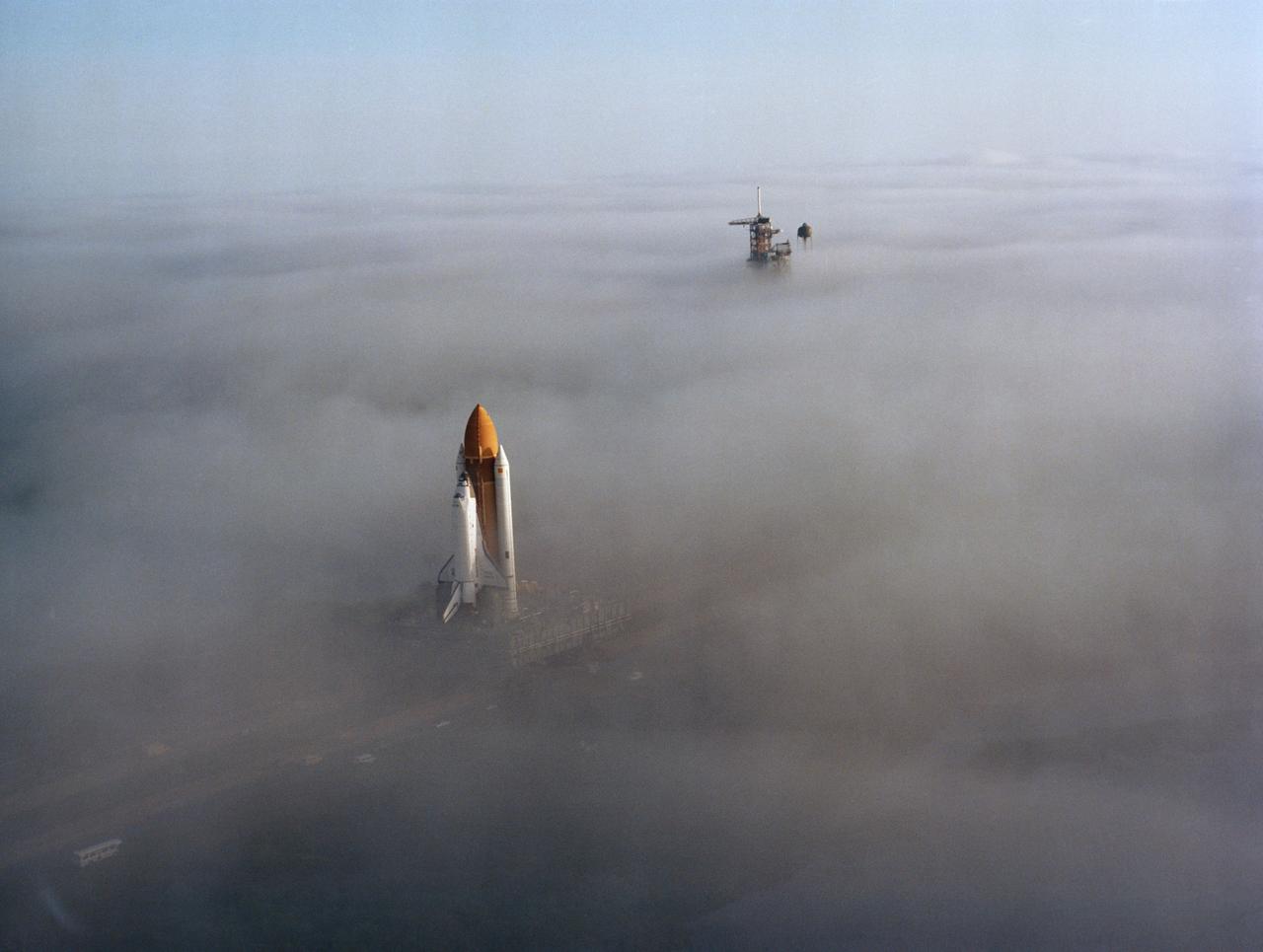 S82-41141 (30 Nov. 1982) --- The space shuttle Challenger, atop a mobile launch platform, slowly moves through the Florida fog to Launch Pad 39A in preparation for its first liftoff early next year. The fully assembled shuttle, weighting 12,000 pounds less than predecessor Columbia, completed the trip in just over six hours. Photo credit: NASA