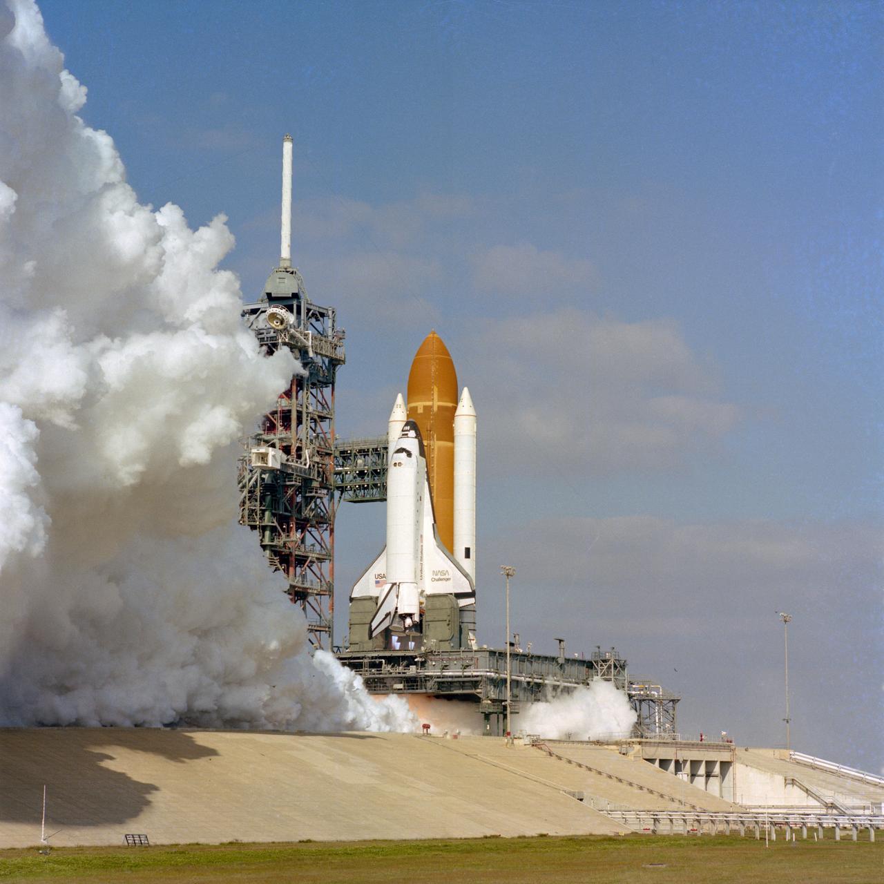 The Space shuttle orbiter Challenger is given a 20-second test firing of its new main engines on December 18, 1982 on pad 39A at the Kennedy Space Center. This test was the first time these engines ahd been tested in the clustered flight configuration.