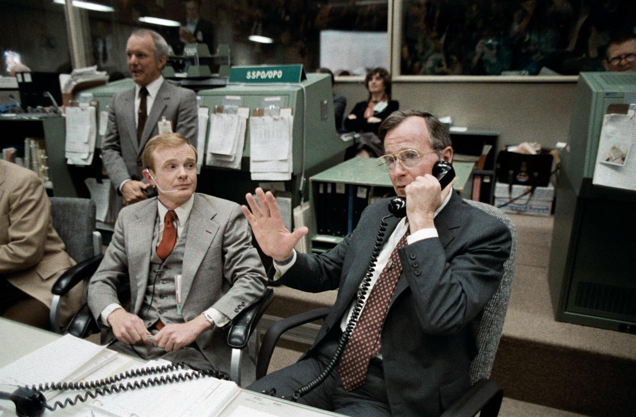 S83-30192 (8 April 1983) --- Vice President George Bush talks to the Earth-orbiting STS-6 astronauts from the spacecraft communicators; (CAPCOM) console in the mission operations control room (MOCR) of the Johnson Space Center?s mission control center.  Astronaut Roy D. Bridges, is one of the CAPCOM personnel on duty.  JSC Director Gerald D. Griffin, left, watches a large monitor (out of frame) on which the TV scene of the four-member Challenger crew is visible.  This photo was made by Otis Imboden.