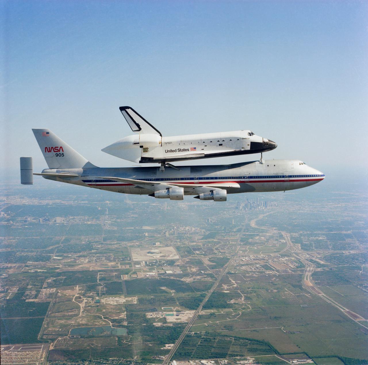 S83-30237 (16 April 1983) --- Downtown Houston and southern portions of that city form the backdrop for this picture of the Space Transportation System?s Challenger flying to the Kennedy Space Center in Florida from its California landing site. It is ferried by NASA 905, a modified 747 aircraft. The crew inside the 747 was as follows: Pilot Joseph S. Algranti; Co-pilot Francis R. (Dick) Scobee; Flight Engineers Louis E. (Skip) Guidry Jr. and Glen O. Pingry. The frame was exposed by Bob Gray from the rear station of a nearby T-38 chase plane piloted by David L. Mumme. The Harris County Domed Stadium (Astrodome) can be seen near center. Photo credit: NASA