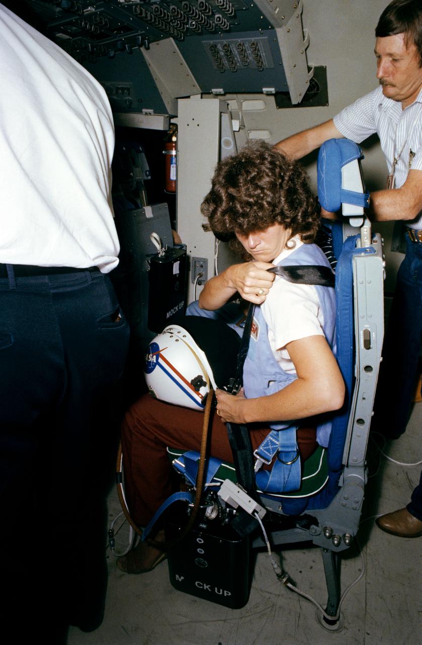 S83-32568 (23 May 1983) --- Astronaut Sally K. Ride, STS-7 mission specialist, straps herself into a seat in the Shuttle Mission Simulator (SMS) in Johnson Space Center?s Mission Simulation and Training Facility. Dr. Ride and the other STS-7 crew members continue their simulations in the motion base simulator in preparation for their flight in the space shuttle Challenger. Launch is scheduled for June 18. Troy Stewart, suit technician, assisted Dr. Ride. Photo credit: NASA