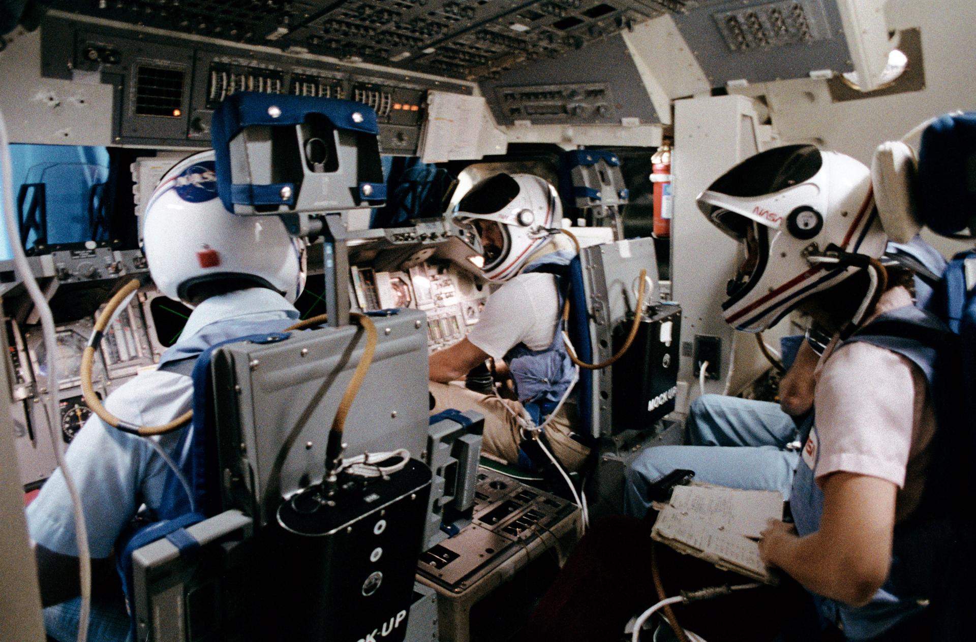 Crew members sit in a mock-up shuttle simulator for training