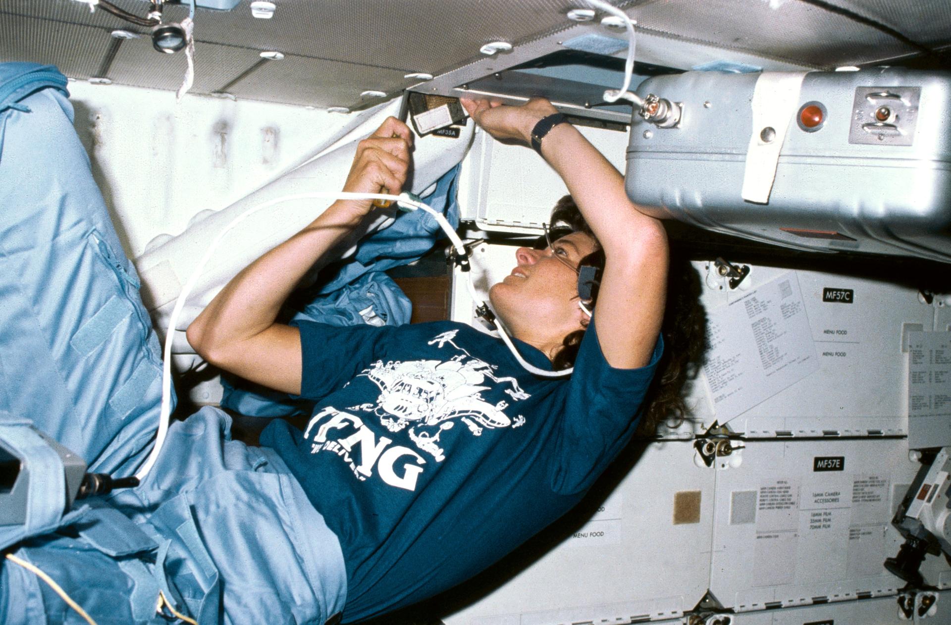 Astronaut Sally K. Ride uses a screw driver in order to clean out an air filtering system