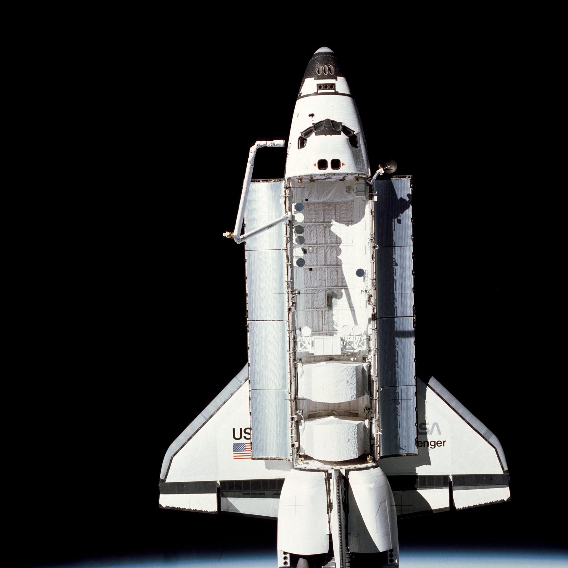 STS-7 orbiter with cargo bay doors open set against the darkness of space