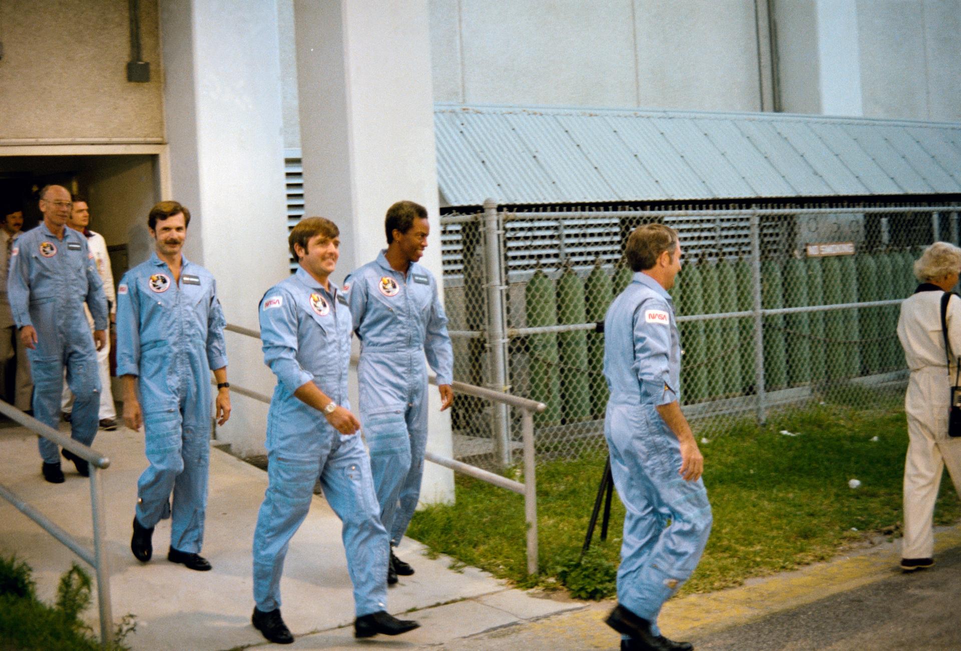 The crew of STS-8 walks out of the operations and checkout building at KSC during a launch rehearsal