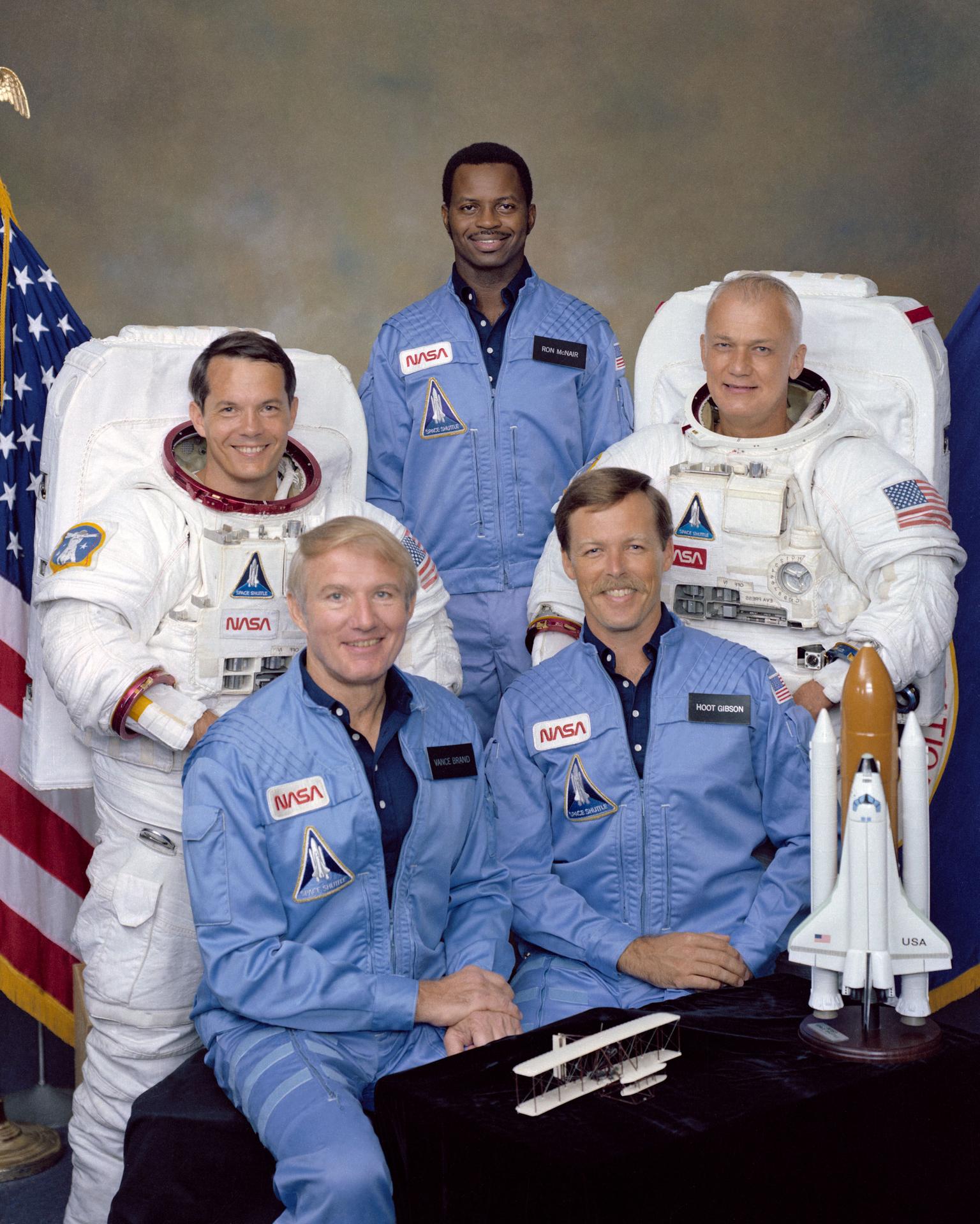 Five astronauts pose for crew portrait with model shuttle and US flag