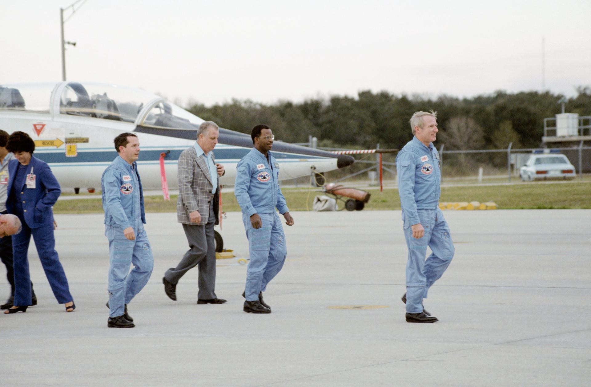 Crew of STS-41B walking in front of a T-38 aircraft