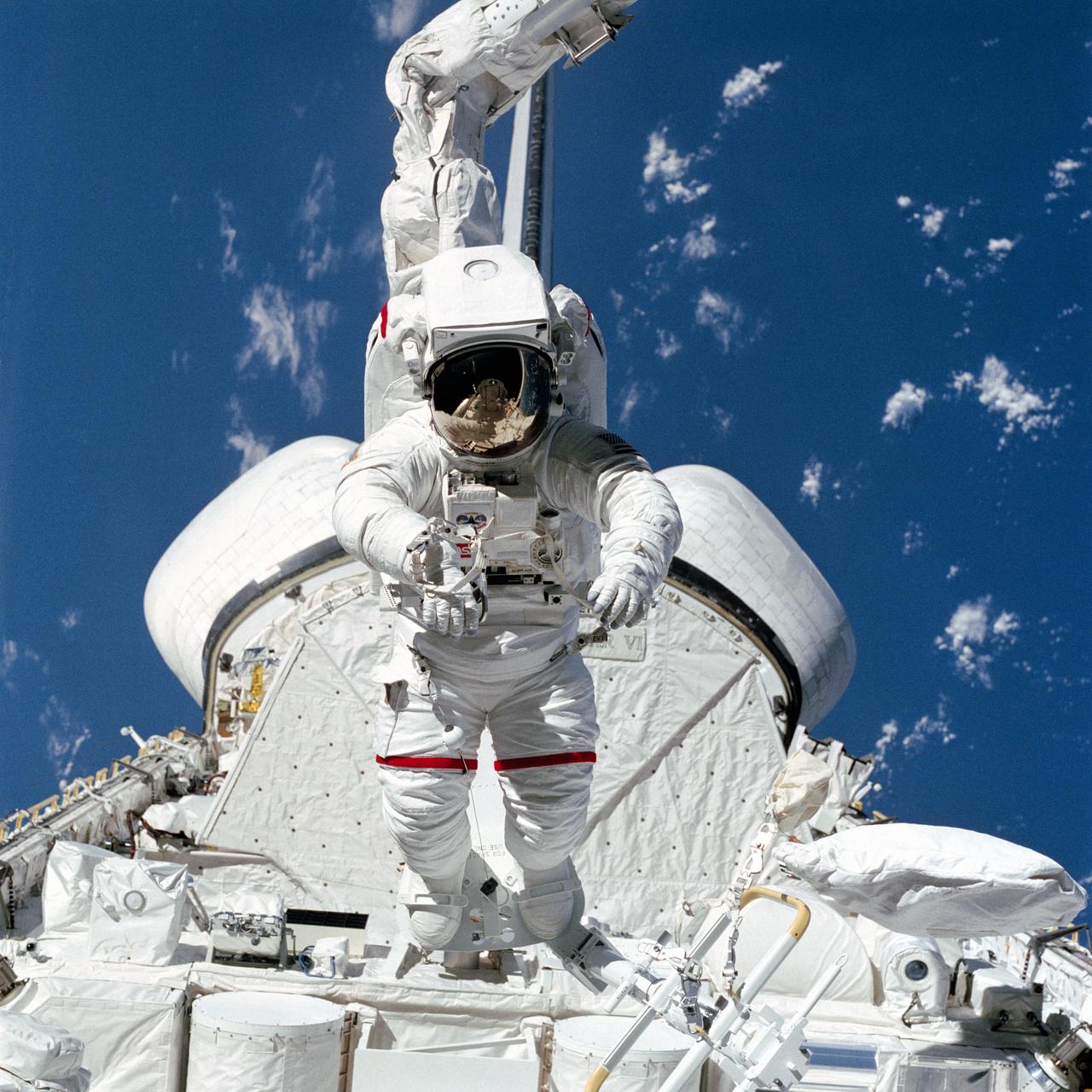 S84-27039 (7 Feb 1984) --- Astronaut Bruce McCandless II, at first glance appears to be walking on cargo in the Space Shuttle Challenger's payload bay. Actually, he is being "flown" around above the stationary cargo.  His "flight" is due to the combined configuration of the Mobile Foot Restraint (MFR) and the Remote Manipulator System (RMS). His helmet visor reflects in miniature parts of the payload bay that can't be seen in the larger portion of the photo.  A 70mm camera aimed through the aft flight deck windows exposed this frame.