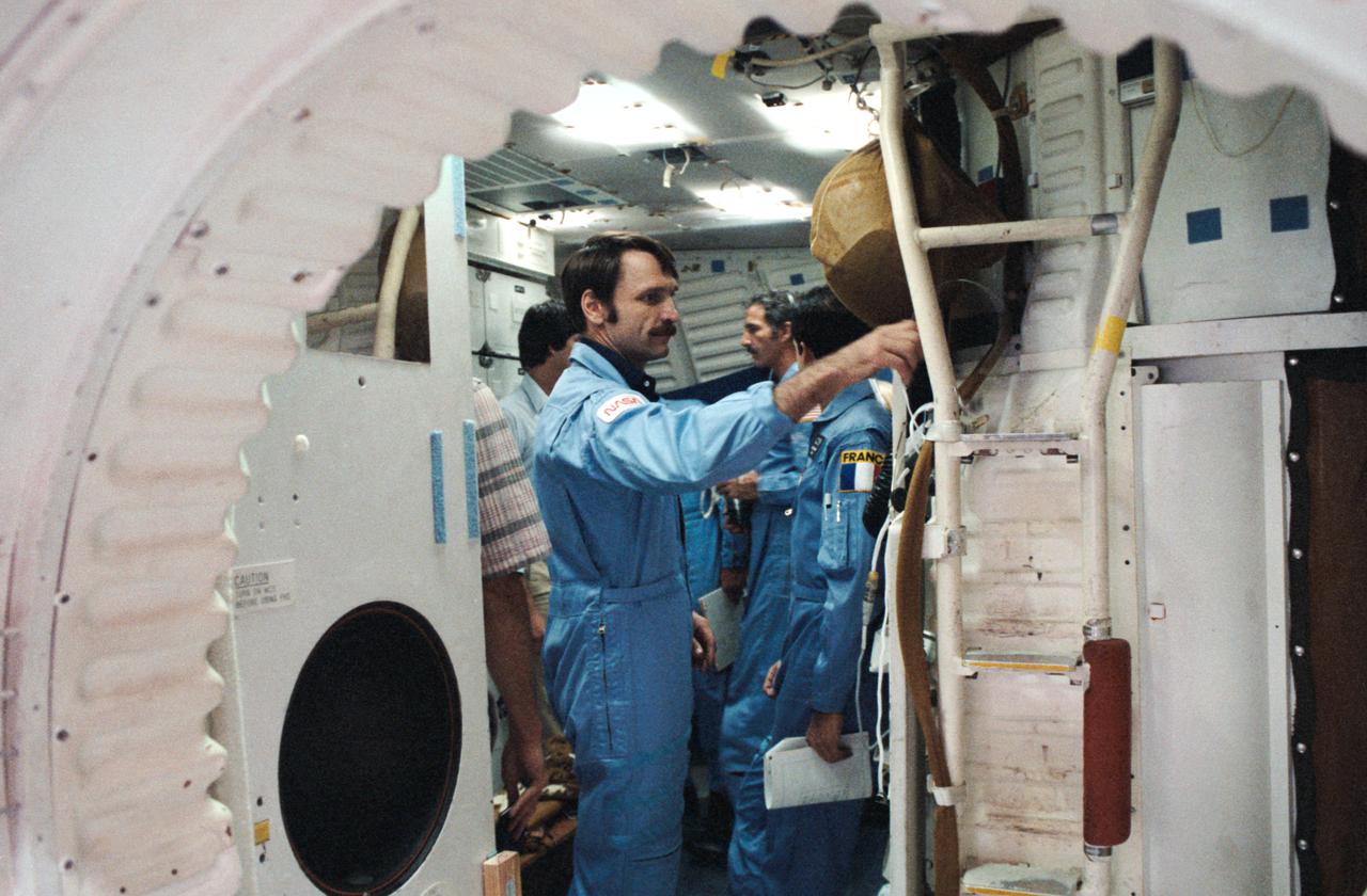 STS 51-E crew is briefed on the Shuttle full fuselage trainer. Astronauts Dave Griggs (foreground), Jean Loup Chretien (behind Griggs) and Jeff Hoffman are being shown the workings of the trainer by flight instructors.
