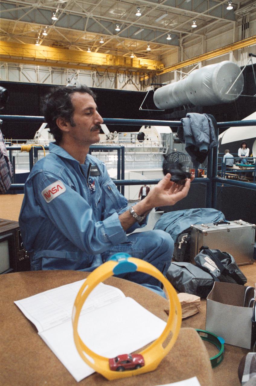 STS-51E Crewman Jeff Hoffman in 1-G Trainer with space experiment toys and camera, 01/17/1985, .                  1.  STS-51E - EXPERIMENTS (TOYS)                   JSC, HOUSTON, TX                  Also available in 35 B&W