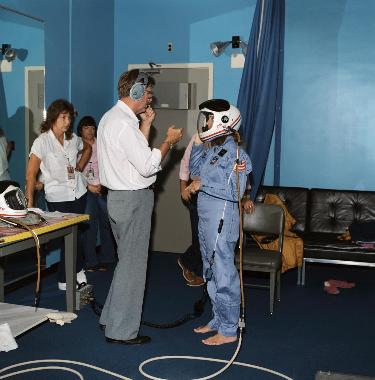 S85-40031 (November 1985) --- Payload specialist Sharon Christa McAuliffe is briefed on launch/entry helmets by crew systems technician Alan M. Rochford in the Johnson Space Center’s crew systems lab. McAuliffe is one of seven crew members in training for STS-51L flight scheduled for January 1986. Photo credit: NASA