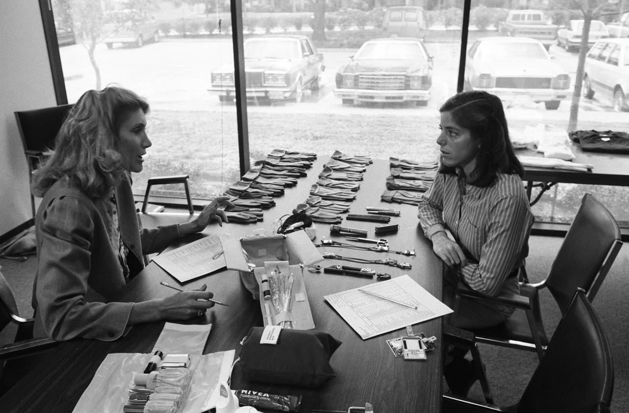 Views of STS-33/51L crew personnel Prime McAuliffe and Backup Morgan at the ILC Facility during clothing selection and Building #37 during food sampling, and with the rest of the STS-33/51L crew.    40074: "Teacher-in-Space" Participant Barbara Morgan (right) is briefed on her suit and on personal hygiene equipment to be used on the STS-51L Mission.     1. JSC - Education Program (Teacher in Space)  2. Barbara Morgan  3. Christa McAuliffe  4. STS-33/51L - Crew Training (Uniforms/Food/Crew)
