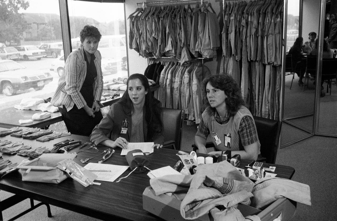Teacherin-Space participant Christa McAuliffe (right) is briefed on her suit and on personal hygiene equipment to be used on the STS 51L Mission. The briefing was conducted by Laura Louviere (center).