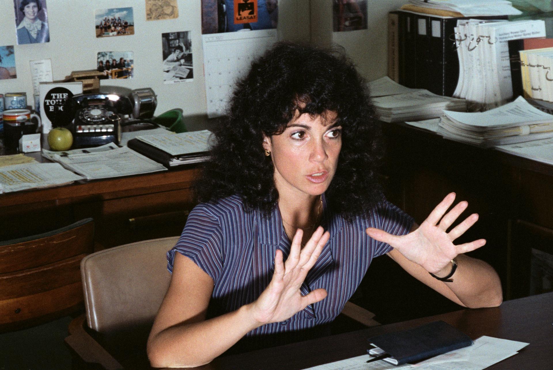 Judy Resnik seated at desk gesticulating with hands