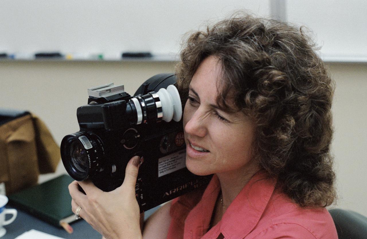 S85-40670 (18 Sept. 1985) --- The two teachers, Sharon Christa McAuliffe and Barbara R. Morgan (out of frame) have hands-on experience with an Arriflex motion picture camera following a briefing on space photography. The two began training Sept. 10, 1985 with the STS-51L crew and learning basic procedures for space travelers. The second week of training included camera training, aircraft familiarization and other activities. McAuliffe zeroes in on a test subject during a practice session with the Arriflex. Photo credit: NASA