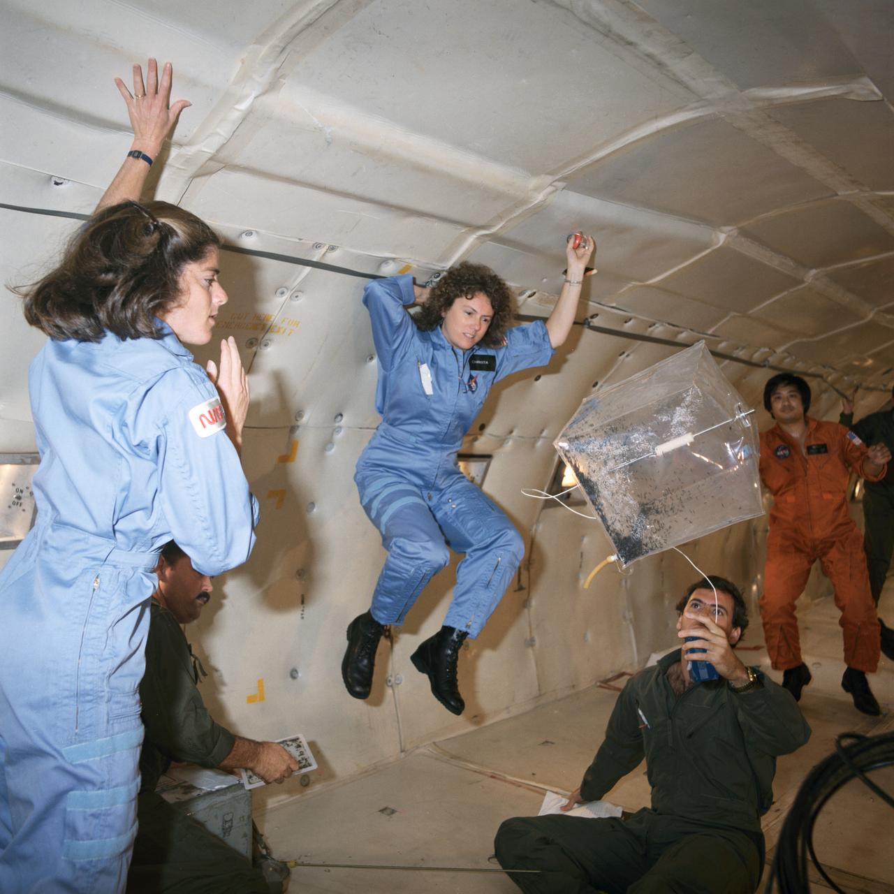 S85-42474 (16 Oct. 1985) --- A KC-135 aircraft provides a brief period of weightlessness as a preview for a teacher, in training to fly onboard a space shuttle for the Teacher-in-Space Project, and her backup. Sharon Christa McAuliffe (center frame), STS-51L prime crew member, and Barbara Morgan, her backup, monitor an experiment involving magnetic effects - one of the tests to be performed on the STS-51L flight. The experiment uses a control box, a square receptacle containing rubber tubing, stainless steel rod, a filter with desiccant, soft iron wire and a magnet. Photo credit: NASA