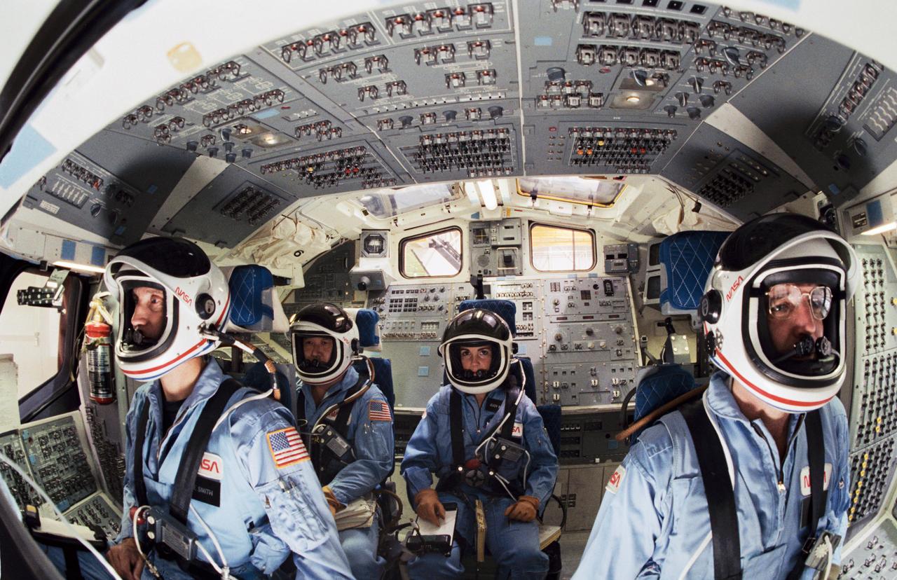 S85-46207 (December 1985) --- Shuttle Mission Simulator (SMS) scene of astronauts Michael J. Smith, Ellison S. Onizuka, Judith A. Resnik, and Francis R. (Dick) Scobee in their launch and entry positions on the flight deck. The photo was taken by Bill Bowers. Photo credit: NASA