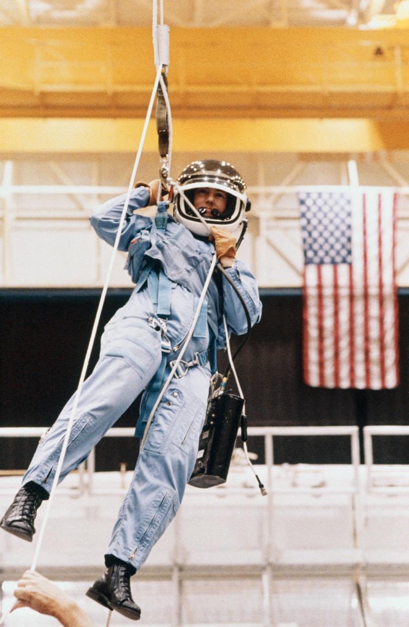 S86-25183 (for release January 1986) --- Sharon Christa McAuliffe, STS-51L payload specialist representing the Teacher-in-Space Project, descends from a mock-up of the space shuttle using a sky-genie device during an emergency training session in the Johnson Space Center?s (JSC) Shuttle Mock-up and Integration Laboratory. The photograph was taken by Keith Meyers of the New York Times.    EDITOR?S NOTE: The STS-51L crew members lost their lives in the space shuttle Challenger accident moments after launch on Jan. 28, 1986 from the Kennedy Space Center (KSC). Photo credit: NASA