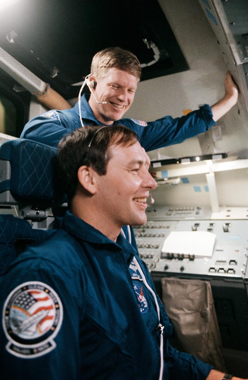 S88-27505 (3 Feb. 1988) --- Astronauts William M. Shepherd (standing) and Jerry L. Ross, both STS-27 mission specialists, get in some training time on the flight deck of the Shuttle Mission Simulator in the Jake Garn Mission Simulation and Training Facility at NASA's Johnson Space Center. Photo credit: NASA