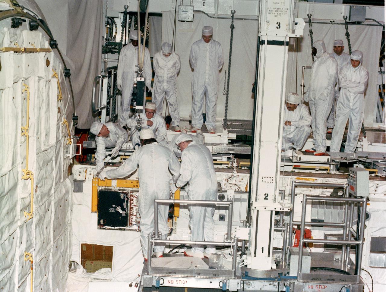 S88-37764 (18 April 1988) --- OASIS, instrumentation which will record the environment experienced by Discovery during the STS-26 Space Shuttle mission, is lowered into position for attachment to the orbiter's aft port sill.  Instrumentation sensors in the payload bay which are connected to the tape recorder module will document a variety of environmental measurements during various phases of the flight including temperature, pressure, vibration, sounds, acceleration, stress, and strain.  OASIS will also record data during the Flight Readiness Firing.  NASA is flying OASIS aboard Discovery in support of the Inertial Upper Stage (IUS) program office of the Air Force Space Division.  The system was developed by Lockheed under a NASA contract, funded by the Air Force.