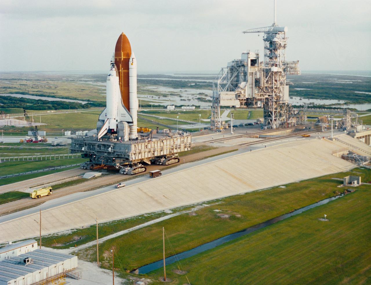 STS-26 Discovery, Orbiter Vehicle (OV) 103, rolls out to Kennedy Space Center (KSC) launch complex (LC) pad 39B on top of the crawler transporter. OV-103 nears LC pad 39B after a six-hour journey from the vehicle assembly building (VAB). When locked onto the nearby rotating service structure (RSS), work will continue to ready the vehicle for the STS-26 launch later in the summer.