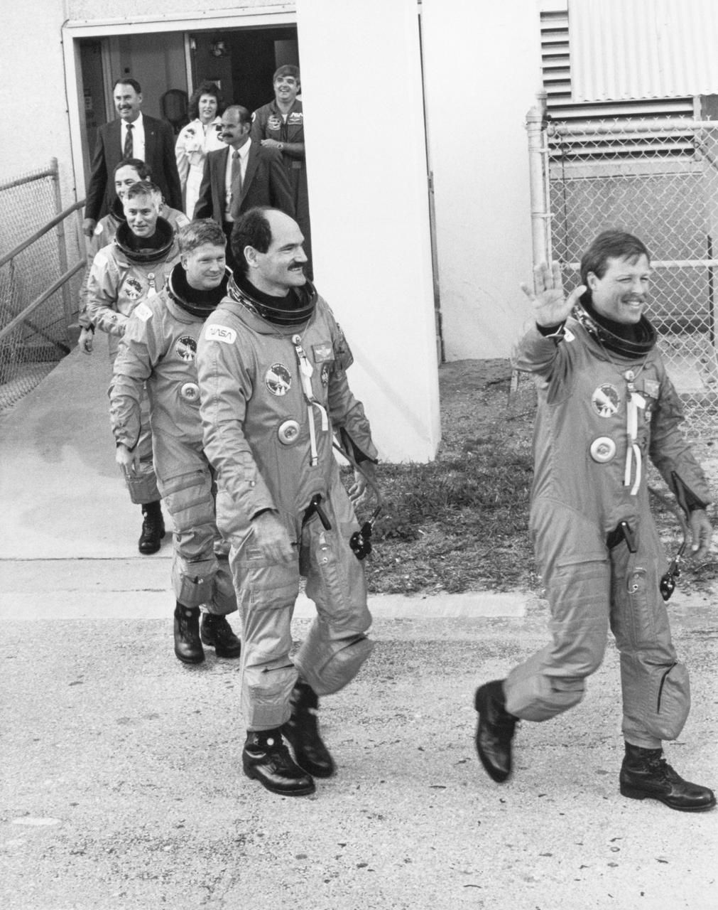 S88-53088 (2 Dec. 1988) --- The STS-27 crew strides down the ramp from the Operations and Checkout Building at Kennedy Space Center to grab a van that will take the crew members to Launch Complex 39 for the Dec. 2, 1988 liftoff of Atlantis. Astronaut Robert L. Gibson, commander, waves to well-wishers (out of frame). He is followed by astronaut Guy S. Gardner, pilot, along with the flight?s three mission specialists -- astronauts William M. Shepherd, Richard M.(Mike) Mullane and Jerry L. Ross. Photo credit: NASA
