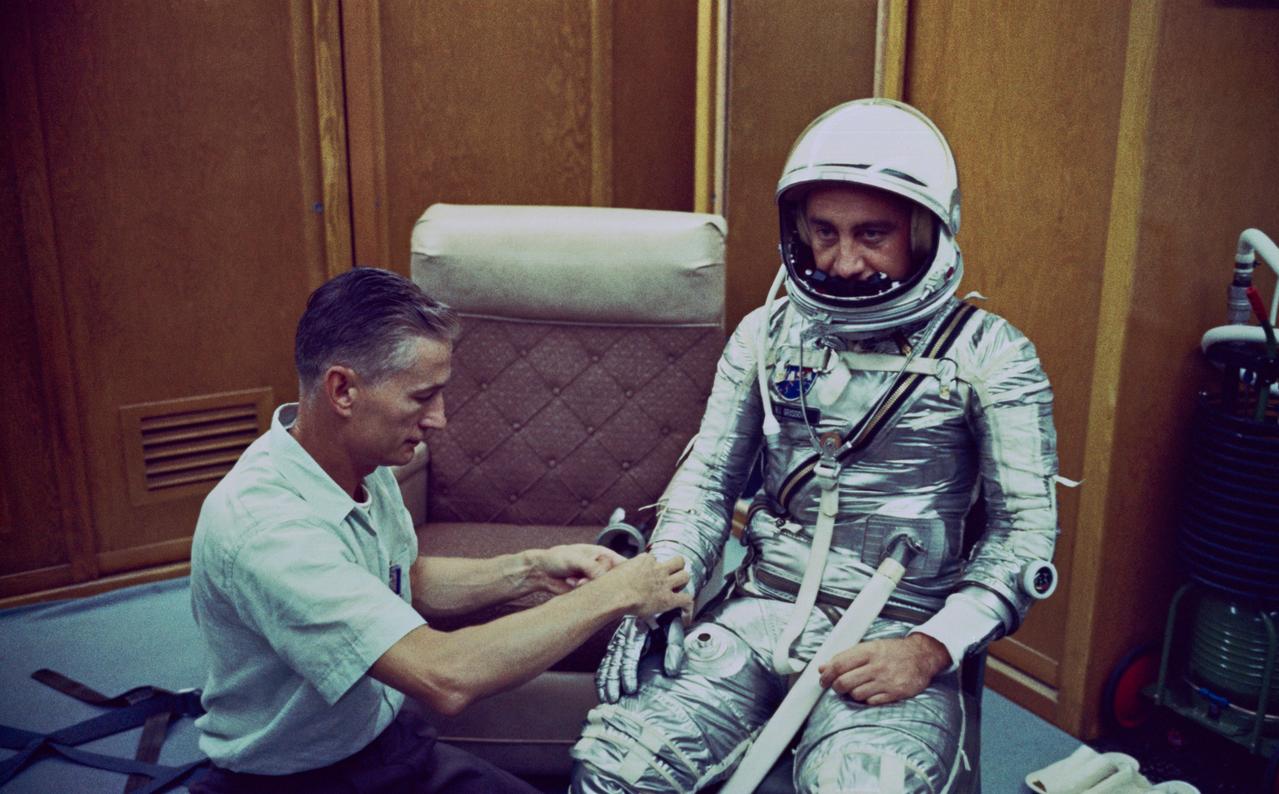 S88-55875 (19 July 1961) --- Donning a spacesuit for the Mercury-Redstone 4 (MR-4) mission, astronaut Virgil I. (Gus) Grissom chats with spaceflight equipment specialist Joe W. Schmitt in the personal equipment room of Hangar S at Cape Canaveral, Florida. Shortly after this photograph was taken, the launch was postponed two days due to unfavorable weather conditions in the area. Photo credit: NASA