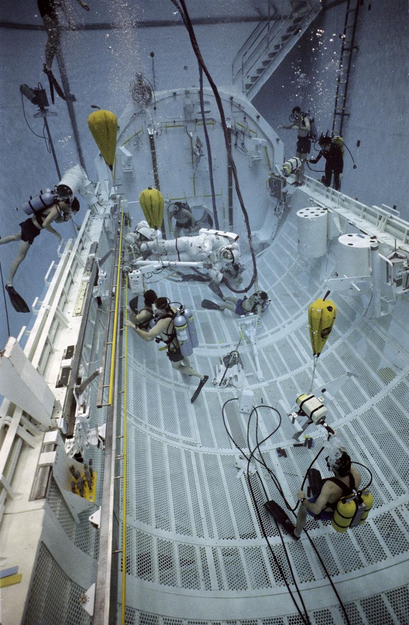 STS-37 Atlantis, Orbiter Vehicle (OV) 104, Mission Specialist (MS) Jerry L. Ross generates electrical power using hand pedals to move crew and equipment translation aid (CETA) cart along a rail during underwater session in JSC's Weightless Environment Training Facility (WETF) Bldg 29. Wearing an extravehicular mobility unit (EMU), Ross operates CETA electrical cart as MS Jerome Apt holds onto the back of the cart. The two crewmembers are practicing a extravehicular activity (EVA) spacewalk they will perform in OV-104's payload bay during STS-37. CETA is a type of railroad hand cart planned as a spacewalker's transportation system along the truss of Space Station Freedom (SSF). SCUBA divers monitor astronauts' underwater activity.