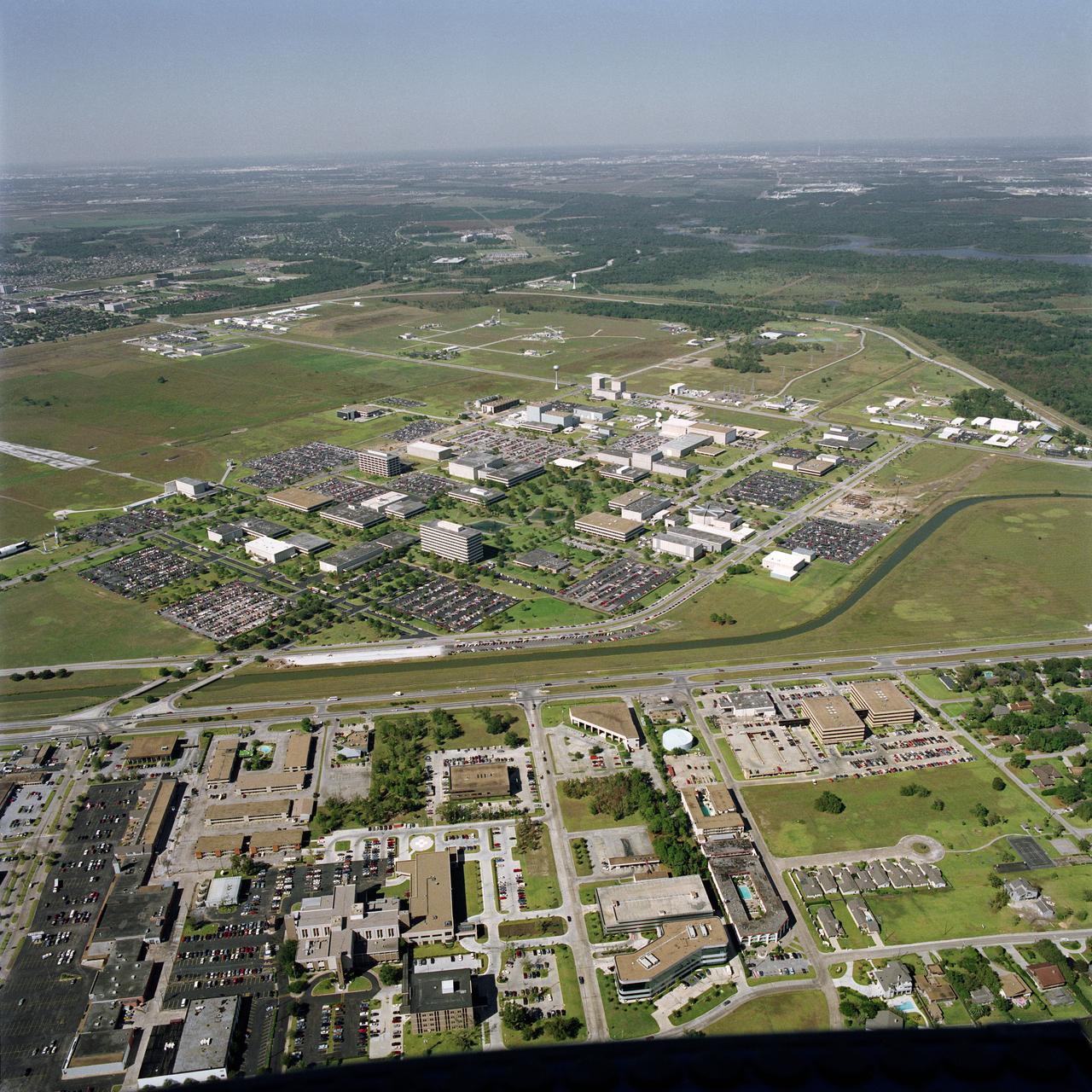 S90-47653 (7 Sept. 1990) --- This aerial photograph of NASA's Johnson Space Center includes the entire 1625-acre site with the exception of a few security-associated facilities and part of the Manned Space Flight Exhibit Complex (AKA "Rocket Park"). The bottom half of the image includes many business and residential edifices as well as a hospital and other medical facilities in the Nassau Bay community. Photo credit: NASA