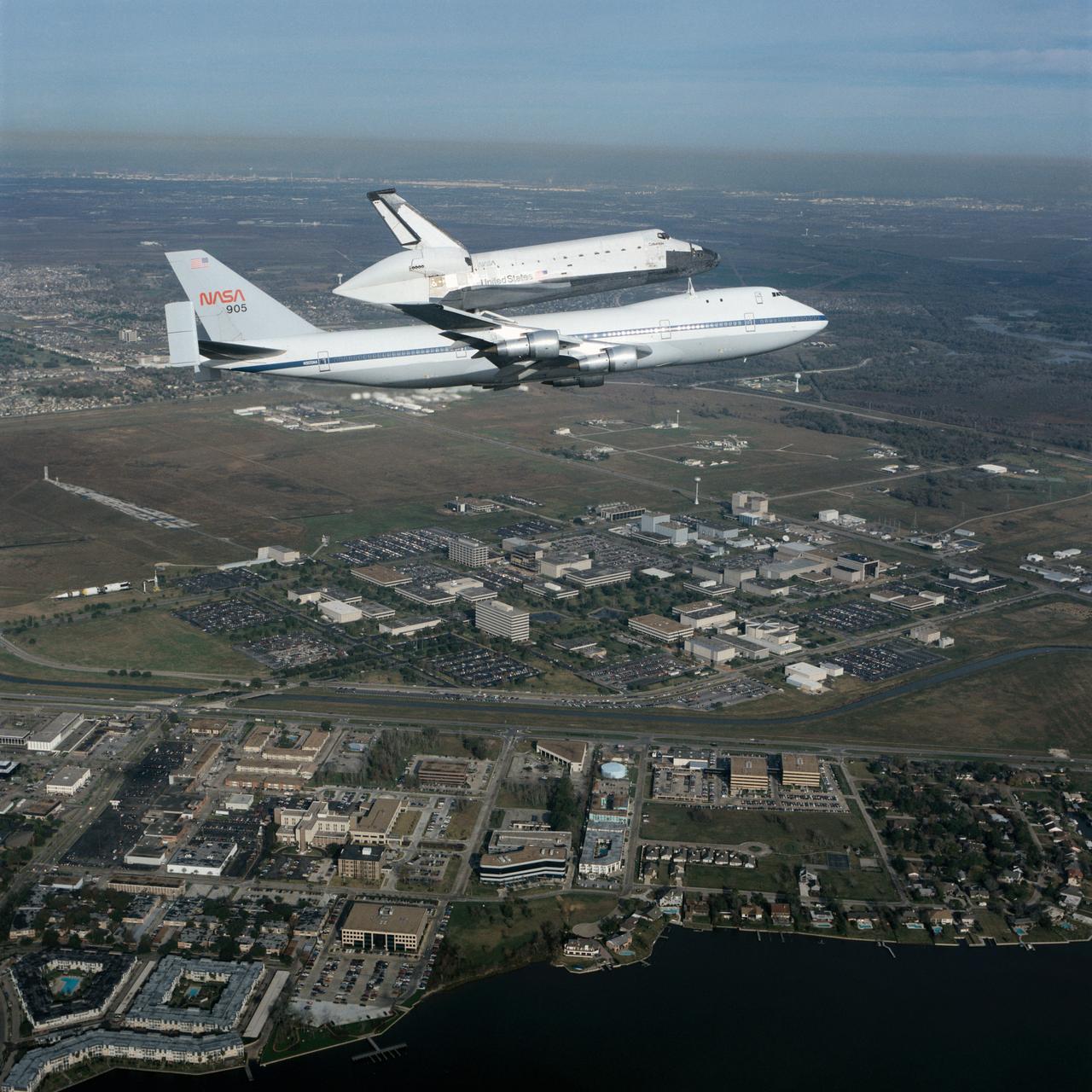 S90-55294 (19 Dec. 1990) --- Johnson Space Center employees and neighbors on the ground didn't get quite this closeup of a view of the Dec. 19 1990 flyover of the Space Shuttle Columbia mounted piggyback atop NASA's Shuttle Carrier Aircraft (SCA--NASA 905). However, hundreds were able to spot it as it passed nearby en route to Florida from California following the successful STS-35 mission. Almost the entire 1625-acre site of the Johnson Space Center is visible in the  background, along with a number of businesses and residences in the nearby municipality of Nassau Bay. The air-to-air photograph was taken by Pete Stanley of JSC's Image Services Division who was a passenger in a T-38 jet aircraft.