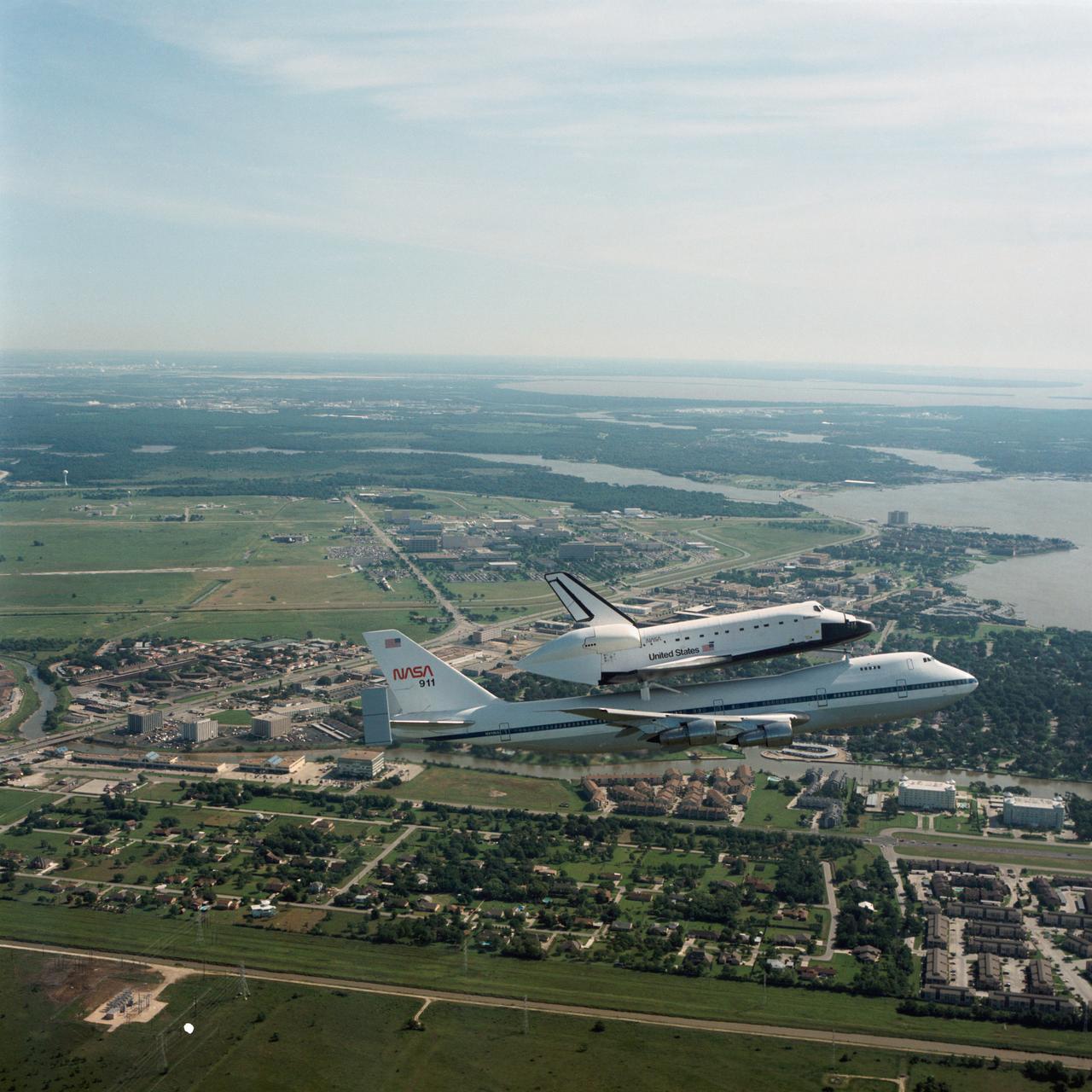 Air to air views of Endeavour, Orbiter Vehicle (OV) 105, transported via the  Shuttle Carrier Aircraft (SCA), NASA 911, on its way to KSC, 05-06-91. JSC with Clear Creek and Egret Bay Blvd in the foreground and Clear Lake and Galveston Bay in the background