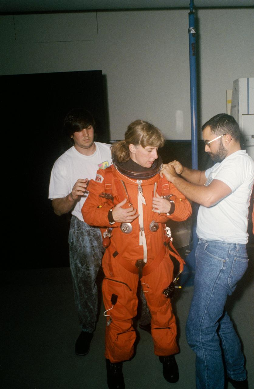 STS-47 Endeavour, Orbiter Vehicle (OV) 105, Mission Specialist (MS) N. Jan Davis, wearing a launch and entry suit (LES), looks on as technicians adjust her LES parachute pack prior to launch emergency egress (bailout) exercises in JSC's Mockup and Integration Laboratory (MAIL) Bldg 9A. Davis is making her first flight in space.