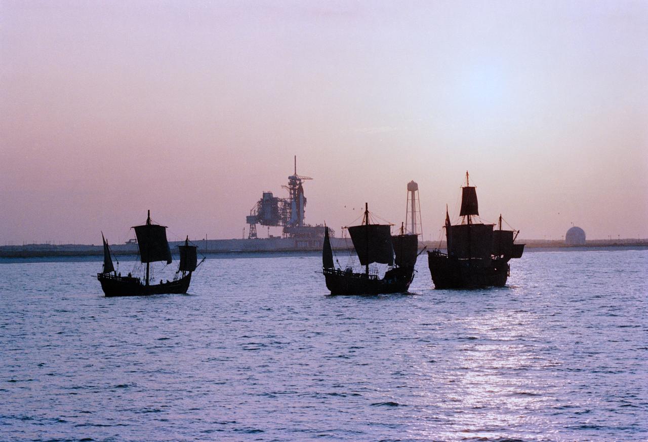 Replicas of Christopher Columbus' sailing ships Santa Maria, Nina, and Pinta sail by Endeavour, Orbiter Vehicle (OV) 105, on Kennedy Space Center (KSC) Launch Complex (LC) Pad 39B awaiting liftoff on its maiden voyage, STS-49. This view was taken from the water showing the three ships silhouetted in the foreground with OV-105 on mobile launcher platform profiled against fixed service structure (FSS) tower and rectracted rotating service structure (RSS) in the background. Next to the launch pad (at right) are the sound suppression water system tower and the liquid hydrogen (LH2) storage tank. View provided by KSC with alternate number KSC-92PC-970.