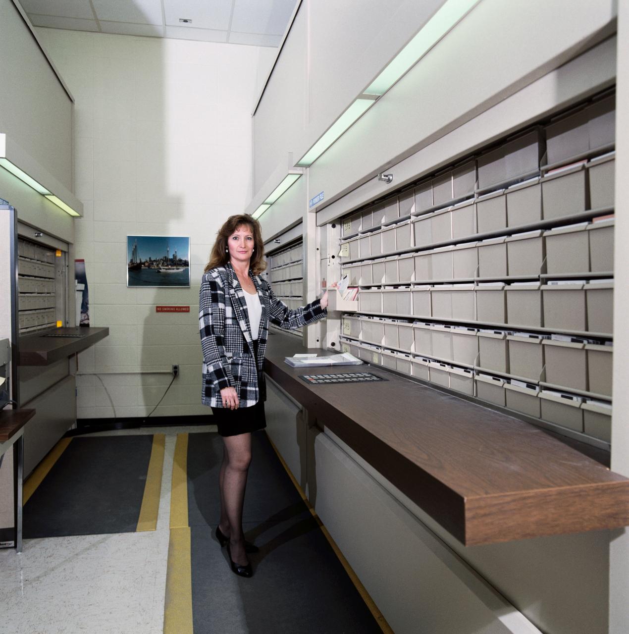 Views of Image Sciences Division activities in bldg 8 and 424 for use in presentation by George Abbey, Deputy Center Director. Views include Taft Broadcasting employee Dexter Herbert in television editing suite in bldg 8 (26624); RMS Photographic Services employee Kelly St. Germaine at IAMS viewing station in the lobby of bldg 8 (26625); RMS employee Irene Jenkins standing in front of automated files used for negative storage in bldg 424 (26626); RMS employee Irma Rodriguez at barcoding and checkout station in bldg 424 (26627).