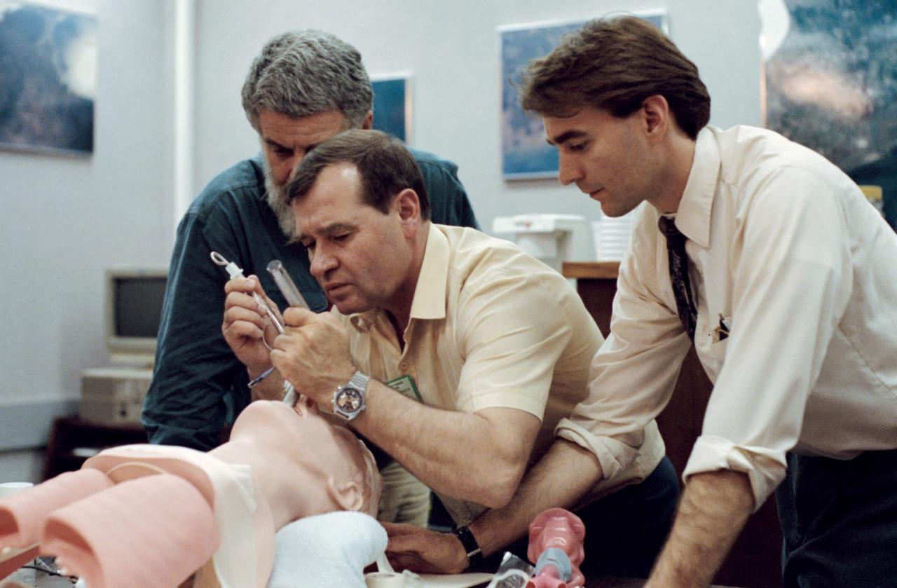 Mir 18 crewmember Gennadiy M. Strekalov, center, practicies an emergency medical procedure to maintain a patient airway during training at JSC. Looking on are Dave E. Ward (right), a JSC medical doctor, and an unidentified interpreter.