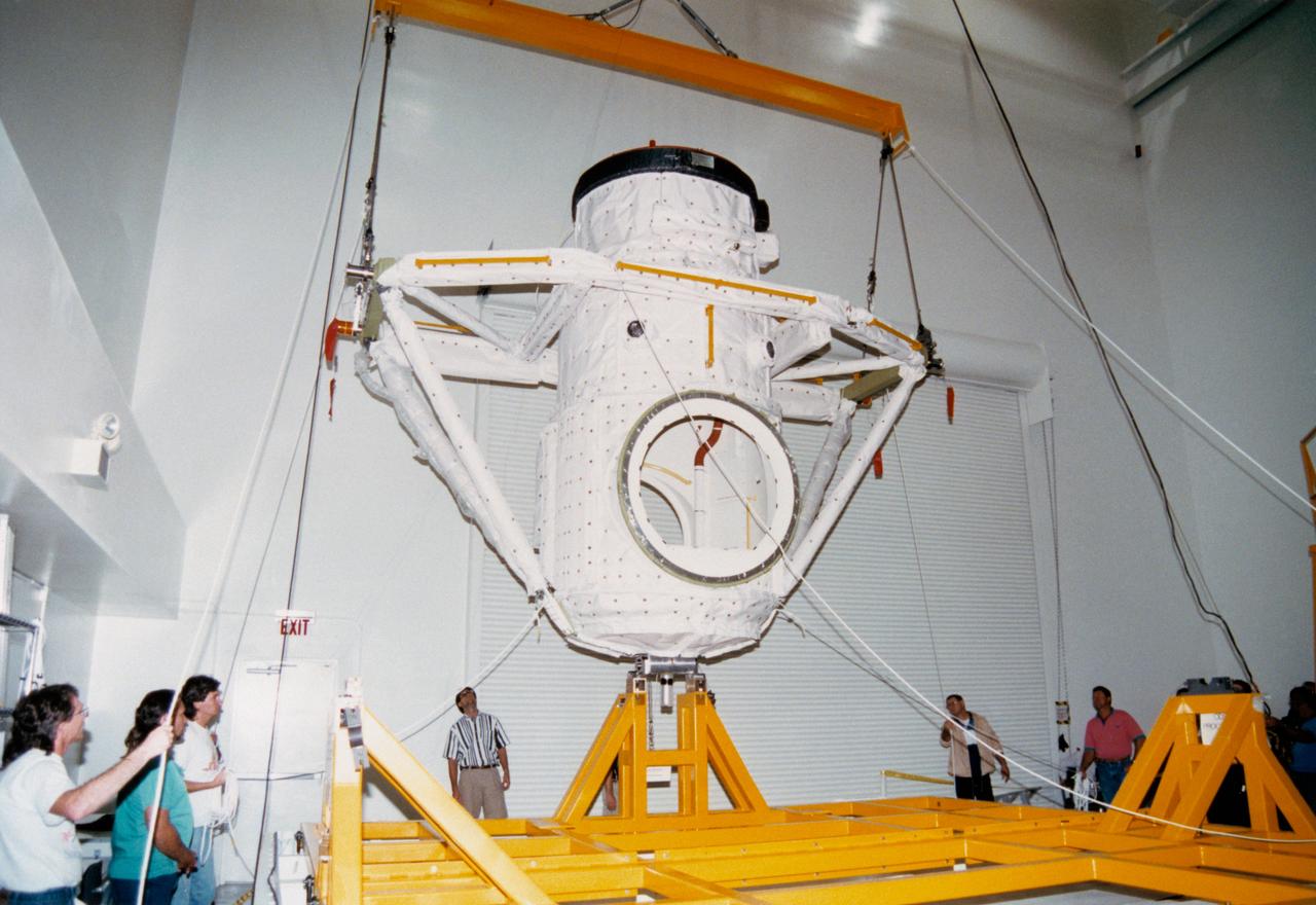 S94-47810 (2 Dec. 1994) --- Lockheed Space Operations Company workers in the Extended Duration Orbiter (EDO) Facility, located inside the Vehicle Assembly Building (VAB), carefully hoist the Orbiter Docking System (ODS) from its shipping container into a test stand. The ODS was shipped in a horizontal position to the Kennedy Space Center (KSC) from contractor Rockwell Aerospace's Downey plant.  Once the ODS is upright, work can continue to prepare the hardware for the first docking of the United States Space Shuttle and Russian Space Station MIR in 1995. The ODS contains both United States-made and Russian-made hardware. The black band is Russian-made thermal insulation protecting part of the docking mechanism, also Russian-made, called the Androgynous Peripheral Docking System (APDS). A red protective cap covers the APDS itself. Other elements of the ODS, most of it protected by white United States-made thermal insulation, were developed by Rockwell, which also integrated and checked out the assembled Russian-United States system.