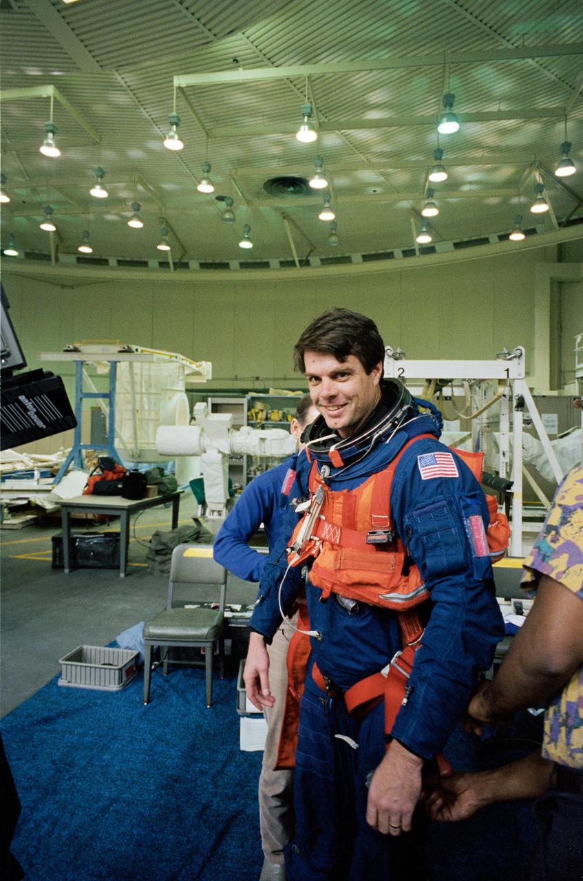 S95-03465 (16 Feb 1995) --- Attired in a training version of the Shuttle launch and entry garment, astronaut Kevin R. Kregel gets help with the final touches of suit donning during a training session at the Johnson Space Center's (JSC) Weightless Environment Training Facility (WET-F).  Assigned as pilot for the STS-70 mission, Kregel was about to rehearse emergency bailout.  The crew members made use of a nearby 25-feet deep pool to practice parachute landings in water and subsequent deployment of life rafts.