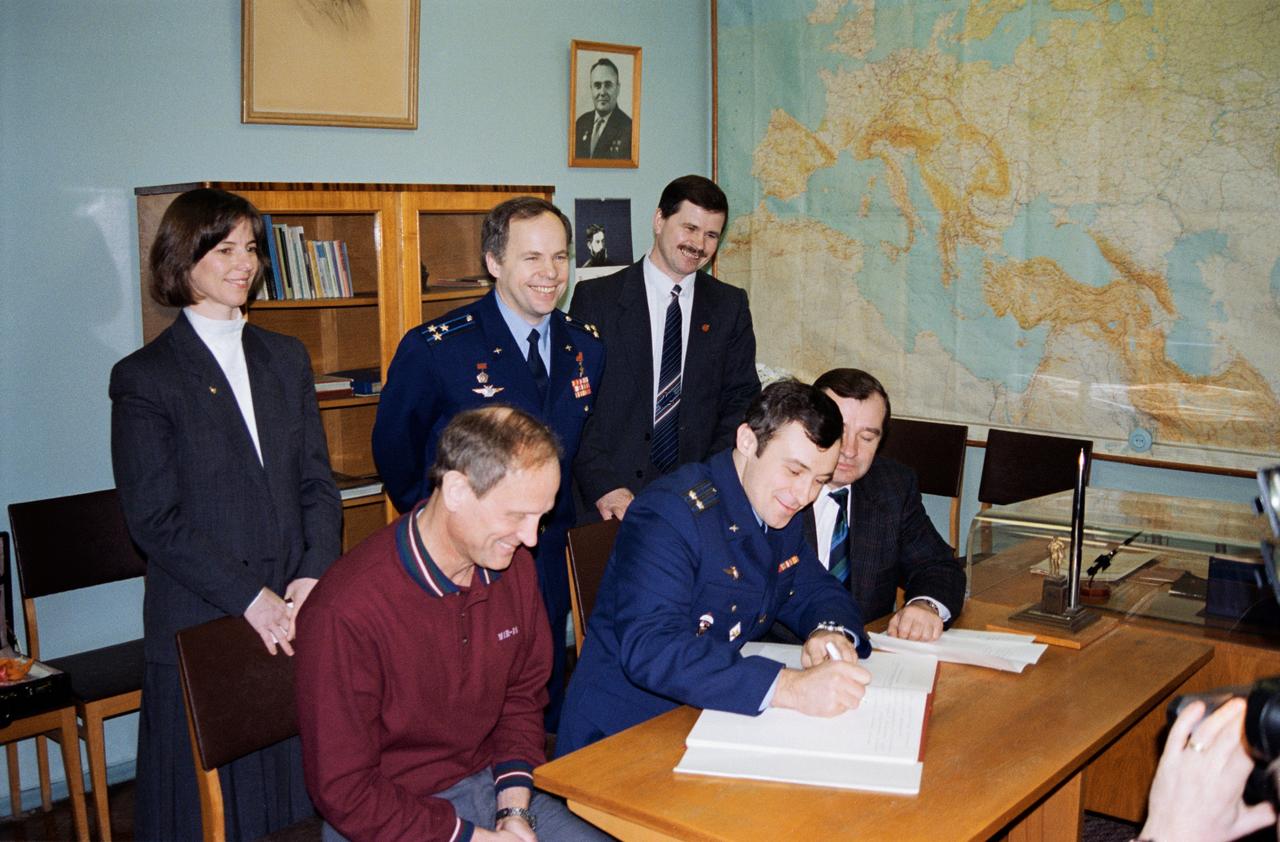 S95-04323 (22 Feb 1995) --- In keeping with Russian tradition, astronaut Norman E. Thagard (seated, left), guest researcher, watches as Vladimir N. Dezhurov (seated, center), signs the diary of the late Yuriy A. Gagarin, the first Russian cosmonaut, as his Mir 18 crew mates and the subsequent Mir crewmembers look on.  Cosmonauts Dezhurov, mission commander, and Gennadiy M. Strekalov (seated right, partially obscured), flight engineer, have been training with Thagard in both the United States and Russia for the past several months.  Watching are, standing left to right, astronaut Bonnie J. Dunbar, Thagard?s alternate crew member; and cosmonauts Anatoliy Y. Solovyev, Mir 19 mission commander, and Nikolai M. Budarin, flight engineer.