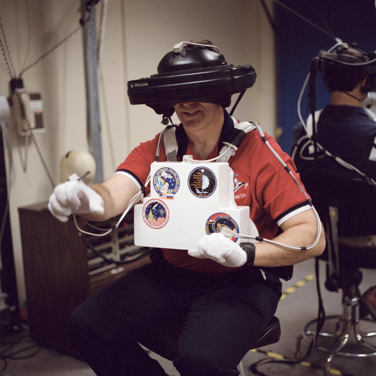 S98-05079 (8 Apr. 1998) --- Astronaut Jerry L. Ross, assigned as a mission specialist for the mission, uses specialized gear to train for his duties aboard the Space Shuttle Endeavour.  This type virtual reality training allows each of the assigned Extravehicular Activity (EVA) astronauts -- Ross and James H. Newman -- to wear a helmet and special gloves to look at computer displays simulating actual movements around the various locations on the International Space Station (ISS) hardware with which they'll be working.  One of those elements will be the Functional Cargo Block (FGB), which will have been launched a couple of weeks prior to STS-88.  Once the FGB is captured using the Remote Manipulator System (RMS) of the Endeavour, astronaut Nancy J. Currie will maneuver the robot arm to dock the FGB to the conical mating adapter at the top of Node 1, to be carried in the Shuttle's cargo bay.  In ensuing days, three EVA space walks by Ross and Newman will be performed to make power, data and utility connections between the two modules.  Currie also uses this same lab to train for her RMS controlling duties.