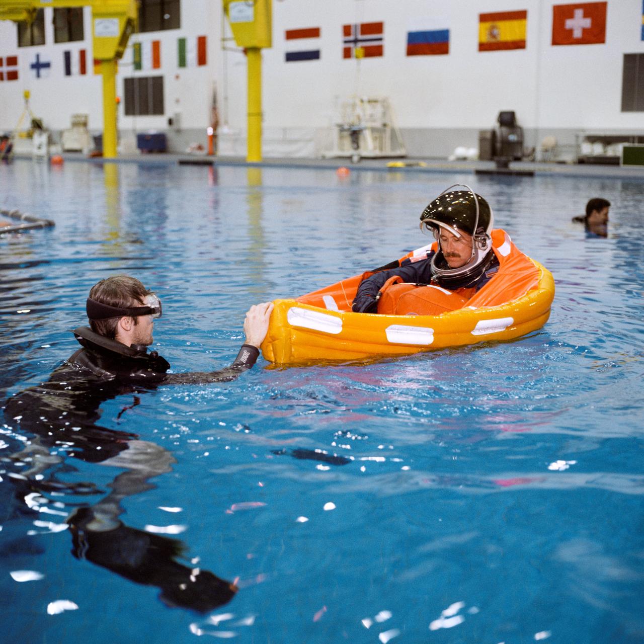 Photographic documentation of the crew of STS-96 conducting bailout training in the Neutral Buoyancy Lab (NBL) pool. Images include: an unidentifiable astronaut in an orange Launch and Entry Suit and helmet being dropped into the pool during training (00580); Mission Specialist (MS) Julie Payette being suspended above the NBL pool prior to being dropped (00581); Julie Payette in her floatation device in the NBL pool (00582-7); Flight Commander Kent Rominger in a blue Launch and Entry Suit (LES) being suspended over the NBL pool prior to being dropped (00589); Mission Specialist (MS) Ellen Ochoa in an orange LES being suspended over the NBL pool prior to being dropped (00590); Pilot Rick D. Husband and MS Daniel T. Barry in floatation devices (00591); closeups of Julie Payette prior to being lifted above the NBL pool (00592-3); MS Tamara E. Jernigan in her floatation device (00594); Julie Payette talking with a NASA employee prior to being raised over the pool (00595); Husband in an orange LES and helmet seated at the poolside talking with a NASA employee (00596); Kominger in his floatation device (00597-8); Barry being assisted with his floatation device at the poolside (00599); Ochoa in her orange LES with helmet talking to NASA personnel at the poolside (00600); Husband in his floatation device operating a transmitter (00601); Rominger splashing Husband (00602); Husband in his floatation device (00603); Barry in an orange LES suspended over the NBL pool prior to being dropped (00604); Ochoa in her floatation device (00605, 00607-8); and Ochoa suspended over the NBL pool with part of her floatation device already inflated (00606).
