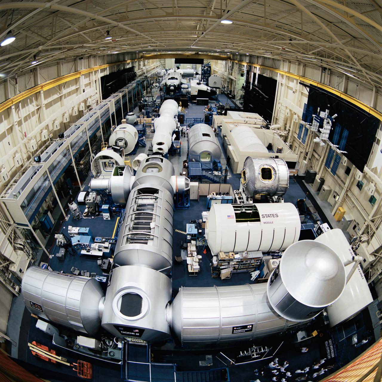 Photographic documentation showing the bldg. 9 ISS module mock-ups and trainers. Views include: various overall views of the configuration of the ISS module trainers on the floor of bldg. 9 (08445-46, 08449-51, 08458-61, 08464-65, 08469, 08471, 08476); various portions of the mock-ups (08447-48, 08470); views of the Node 2, Experiment Module and Logistics Module (08452); Node 2 (08453, 08466); Destiny and Node 2 (08454); Destiny, Unity and Airlock (08455); Zarya, Service Module and shuttle mock-ups (08456); Logistics Module and Experiment Module (08457, 08468); various views of Columbia, Node 2 and Destiny (08462-63); Columbus, Node 2, Experiment Module and Logistics Module (08467); U.S. Laboratory module (08472); Logistics Module (08473); module layout (08474); Logistics Module and Experiment Module (08475).
