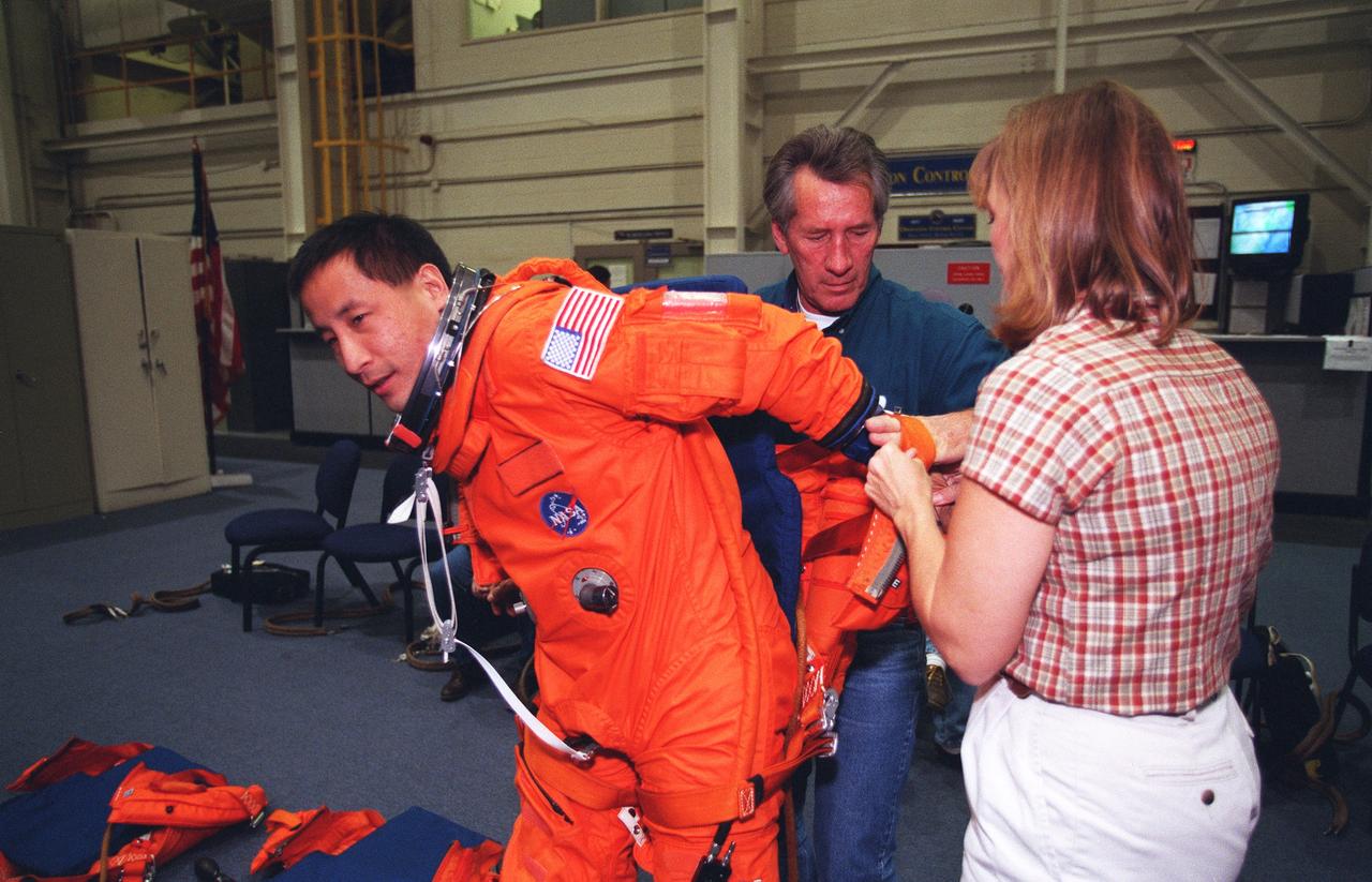 S99-14214 (15 November 1999) --- Astronaut Edward T. Lu, mission specialist, receives assistance with his pressure, ascent and entry garment during emergency egress training at the Johnson Space Center's systems intregration facility. Lu is training with four other astronauts and two cosmonauts for next year's scheduled STS-106 visit to the International Space Station (ISS).