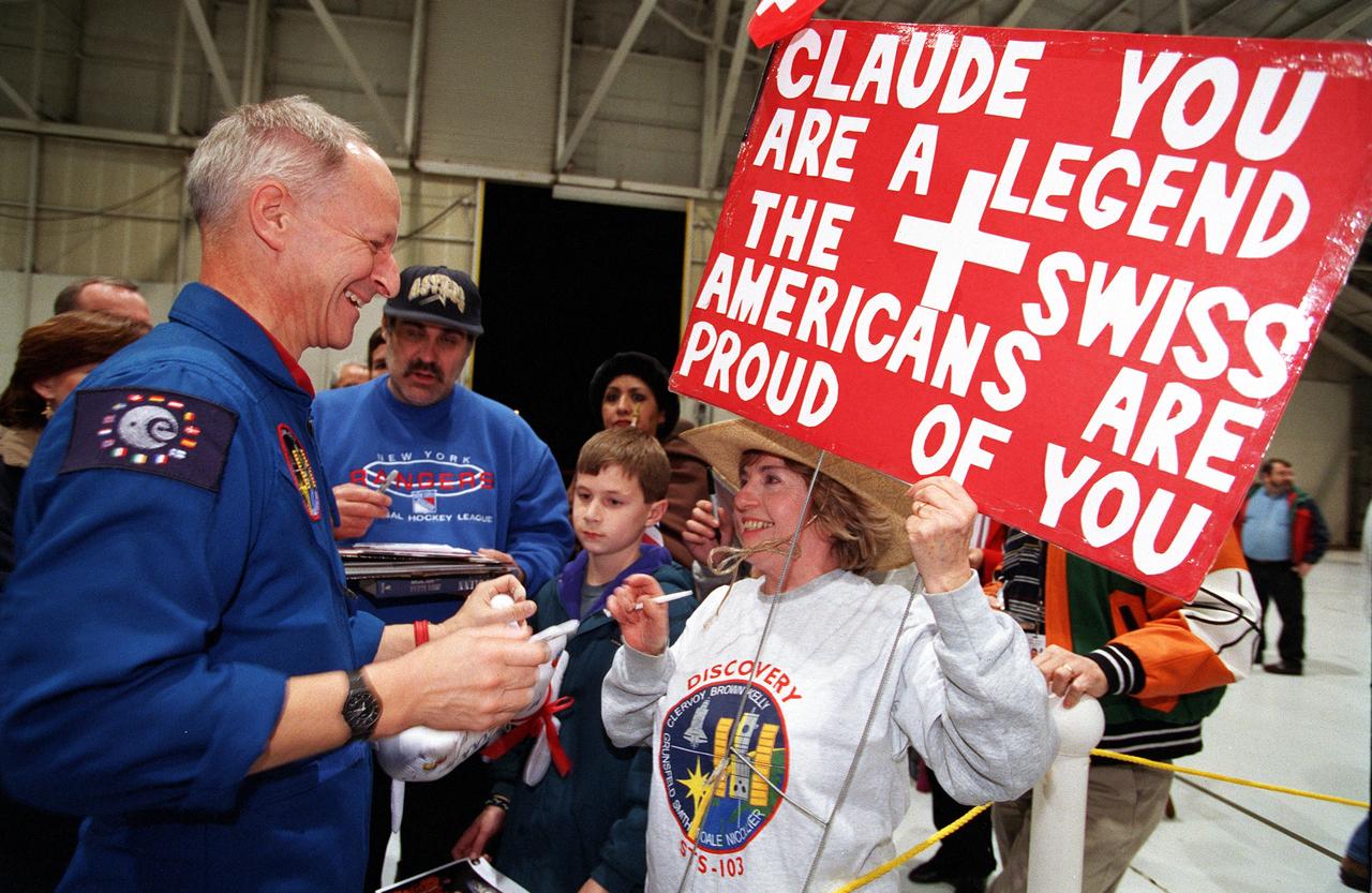 S99-16052 (28 December 1999) --- Astronaut Claude Nicollier, a mission specialist representing the European Space Agency (ESA), is greeted at Ellington Field by a sign-bearing group.