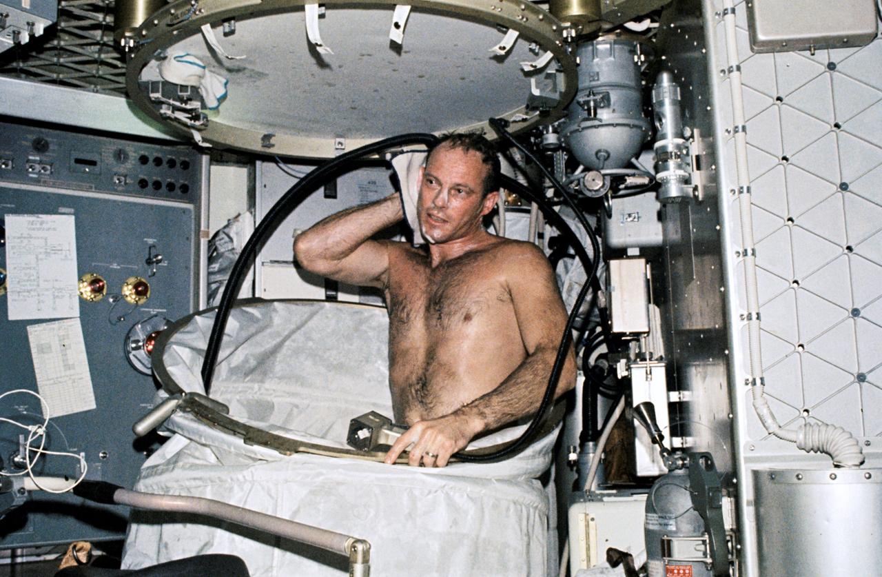 SL3-108-1295 (July-September 1973) --- A close-up view of astronaut Jack R. Lousma, Skylab 3 pilot, taking a hot bath in the crew quarters of the Orbital Workshop (OWS) of the Skylab space station cluster in Earth orbit. This picture was taken with a hand-held 35mm Nikon camera. Astronauts Lousma, Alan L. Bean and Owen K. Garriott remained with the Skylab space station in orbit for 59 days conducting numerous medical, scientific and technological experiments. In deploying the shower facility the shower curtain is pulled up from the floor and attached to the ceiling. The water comes through a push-button shower head attached to a flexible hose. Water is drawn off by a vacuum system. Photo credit: NASA