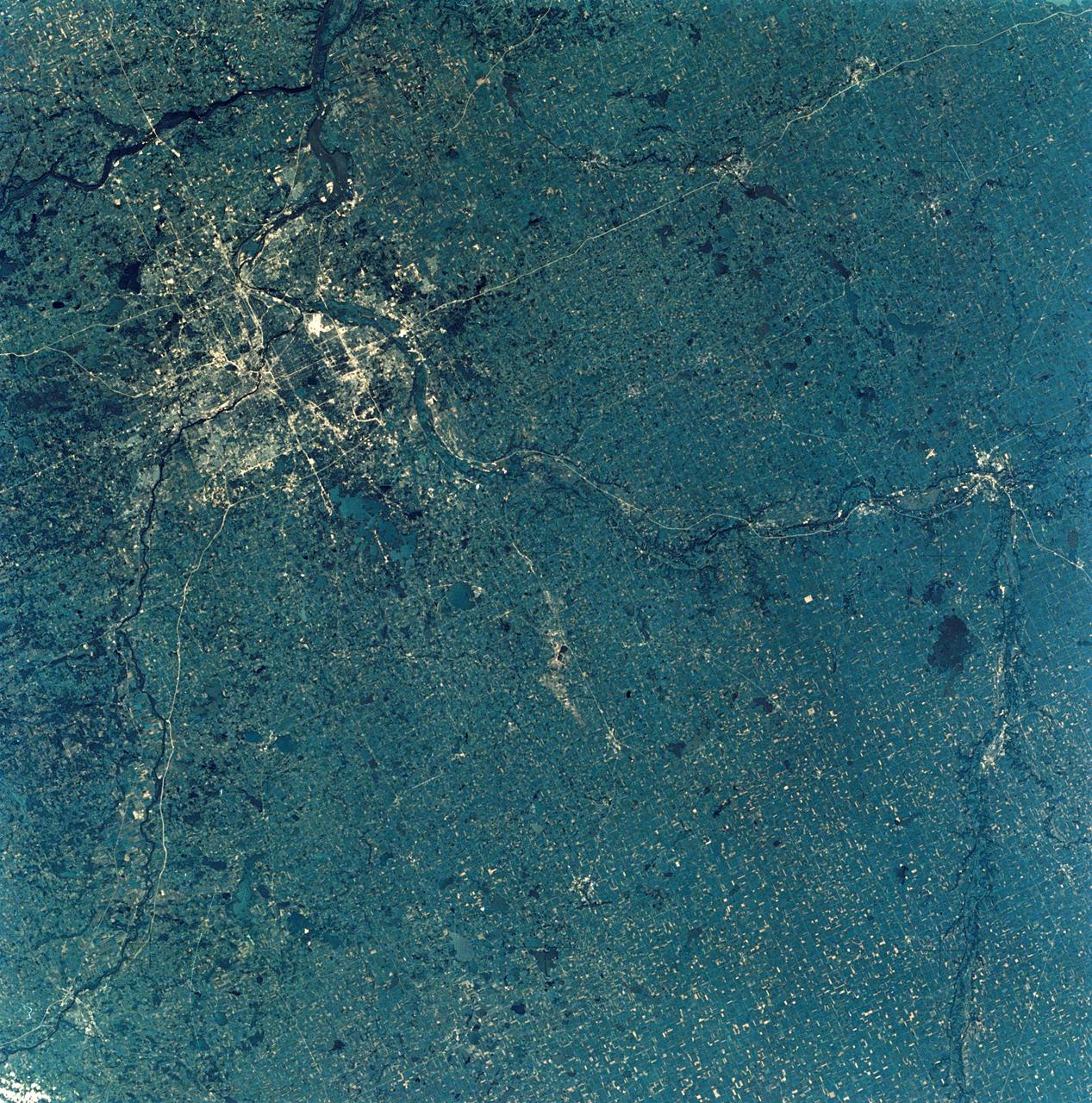 SL3-28-009 (July-September 1973) --- A near vertical view of the Minneapolis-St. Paul, Minnesota area, as photographed from Earth orbit by one of the six lenses of the Itek-furnished S190-A Multispectral Photographic Facility Experiment in the Multiple Docking Adapter of the Skylab space station. A 150mm lens, with SO-356 high definition Ektachrome film, was used to take this picture. The Mississippi River flows southeasterly through this large metropolitan area. Minneapolis is on the west bank of the Mississippi. The Minnesota River makes a large bend at the southern edge of the picture then flows northeasterly to empty into the Mississippi at Minneapolis-St. Paul. The St. Croix River, which serves as a portion of the boundary between Minnesota and Wisconsin, flows into the Mississippi downstream from the twin cities. A long, nearly straight, stretch of Interstate 35 leads southward from Minneapolis-St. Paul. Interstate 94 parallels the Mississippi toward the northwest.  The highway and road network in the area is clearly visible. Note the numerous small lakes in the photograph. This view includes the smaller cities of Hastings, Faribault, Owatonna, Mankato, St. Peter, New Ulm and St. Cloud.  The S190-A experiment is part of the Skylab Earth Resources Experiments Package. Photo credit: NASA