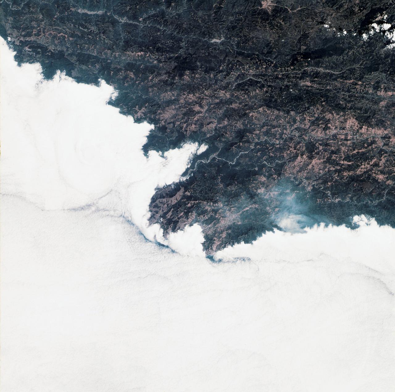 SL3-34-336 (July-September 1973) --- A vertical view of a portion of northern California near the Pacific coast as photographed from Earth orbit by one of the six lenses of the Itek-furnished S190-A Multispectral Photographic Facility Experiment in the Multiple Docking Adapter of the Skylab space station. A cloud deck covers the Pacific Ocean. Most of Cape Mendocino is clear of clouds and extends into the Pacific as the westernmost part of California. The sinuous pattern of the Bel River (in center) flows northward into the ocean and is characteristic of the rivers that drain the coastal ranges.  This area is immediately southeast of Eureka.  During Skylab 3 extensive forest fires occurred near Briceland and the smoke rising from the fires is clearly visible next to the cloud bank. Redwood and fir forests are sources of lumber in this region; and a variety of clear cut (timbering) patterns appear as light against the dark forest. The patterns appear to be related to the topography. Analysis of this photograph will aid Dr. P.G. Langley, Earth Satellite Corporation, in developing methods for forest inventory using space photography. Federal agencies participating with NASA on the EREP project are the Departments of Agriculture, Commerce, Interior, the Environmental Protection Agency and the Corps of Engineers.  All EREP photography is available to the public through the Department of Interior?s Earth Resources Observations Systems Data Center, Sioux Falls, South Dakota, 57198. Photo credit: NASA