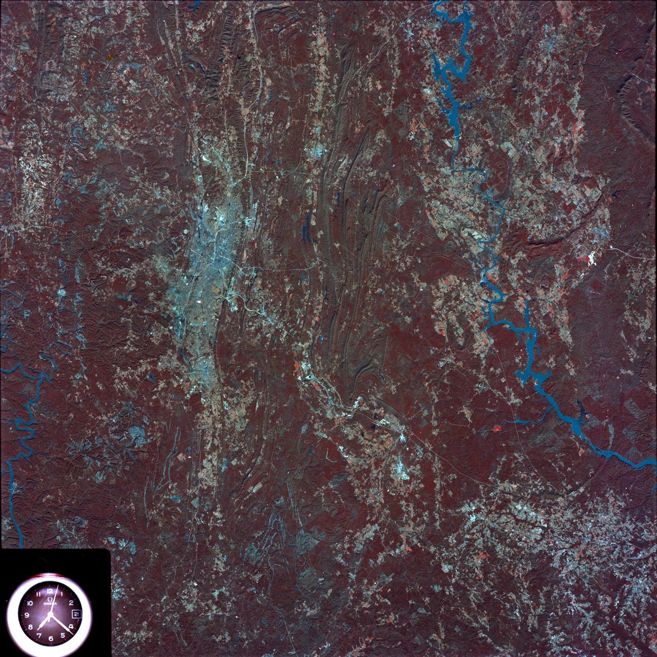 SL4-93-153 (February 1974) --- A vertical view of the Birmingham and central Alabama area is seen in this Skylab 4 Earth Resources Experiments Package S190-B (five-inch earth terrain camera) infrared photographed taken from the Skylab space station in Earth orbit. Illustrated here is the utility of color infrared film in depicting distribution of living vegetation in the 3,600 square mile Birmingham region. The Birmingham industrial complex, with a population of nearly 850,000, is the light gray area nestled in the valley between the northeast-trending ridges that are prominent topographic features in the southern Appalachian Mountains. The narrow ridges and adjacent valleys reflect folded and faulted sedimentary rocks, indicating the complex geological history of the region. Two major rivers and several reservoirs are easily distinguished in this photograph. Bankhand Lake, formed by a dam on the Black Warrior River, appears as bright blue west of Birmingham. Two lakes are formed by dams on the Goosa River east of Birmingham. Federal and state highways appear as thin white lines and are easily identified. Interstate 65 to Montgomery is the prominent white line extending southward from Birmingham. Power line clearings are visible in the center of the picture along the Goosa River, and can be traced northwestward to northern parts of Birmingham. The predominant deep red color of the picture is due to the reflections from living vegetation. In contrast are the light tan areas that commonly occur as rectangular patterns in the east part of the photograph and represent mature agricultural crops or grazing lands. Analysis of the photographic data from the earth terrain camera will be conducted by Dr. H. Jayroe of the Marshall Space Flight Center in developing analytical techniques. All EREP photography is available to the public through the Department of Interior's Earth Resources Observations Systems Data Center, Sioux Falls, South Dakota, 57198. Photo credit: NASA